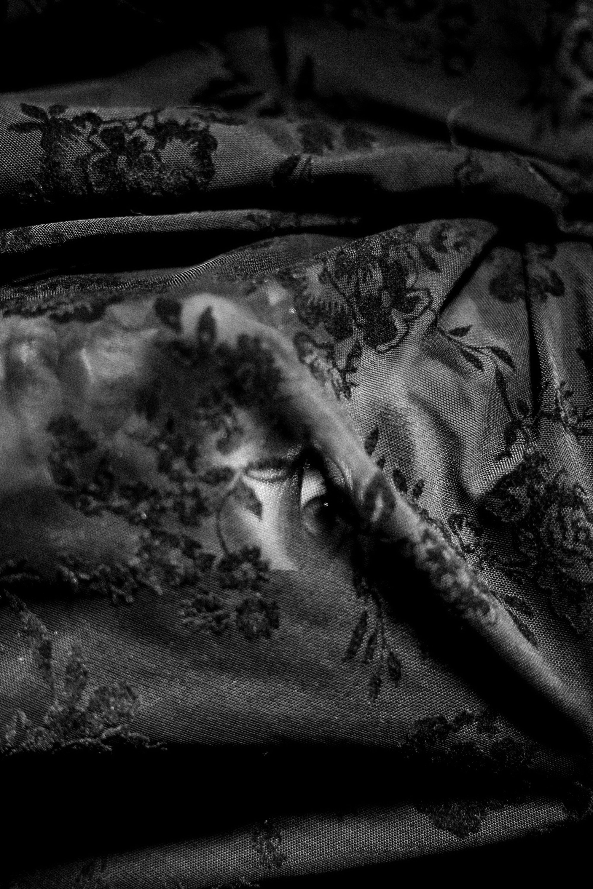 Close-up of a man partially hidden behind patterned fabric in a dimly lit scene.