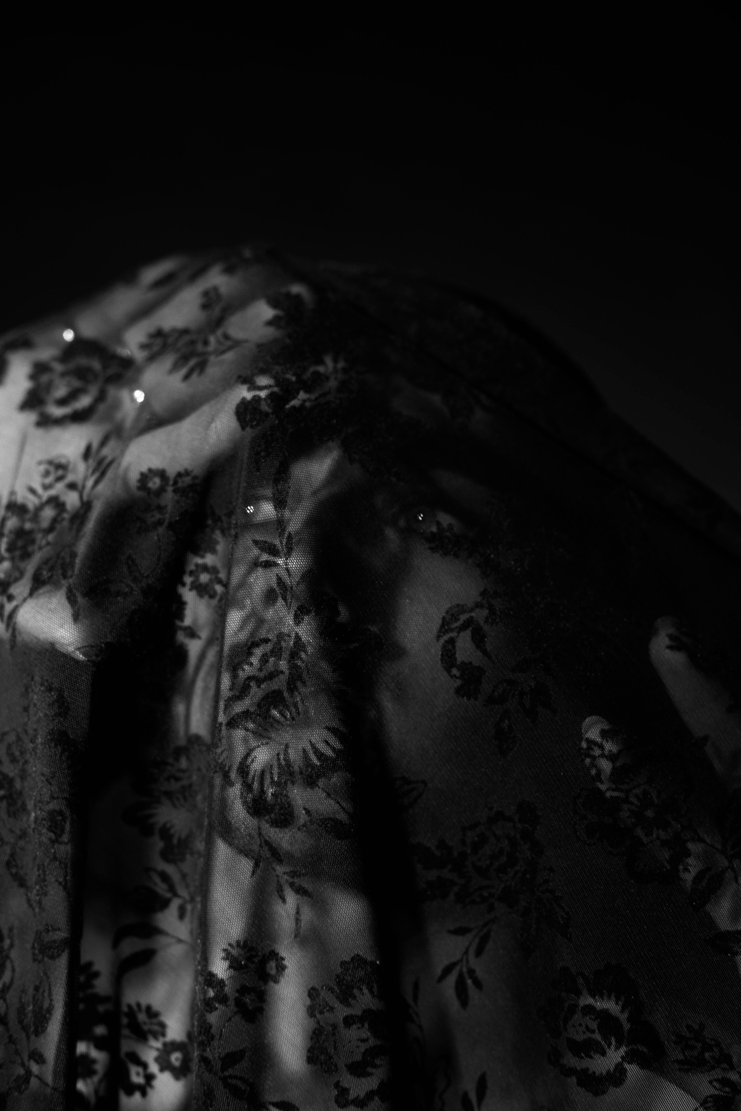 Close-up of dark, sheer floral patterned fabric with gentle folds and subtle light reflection.