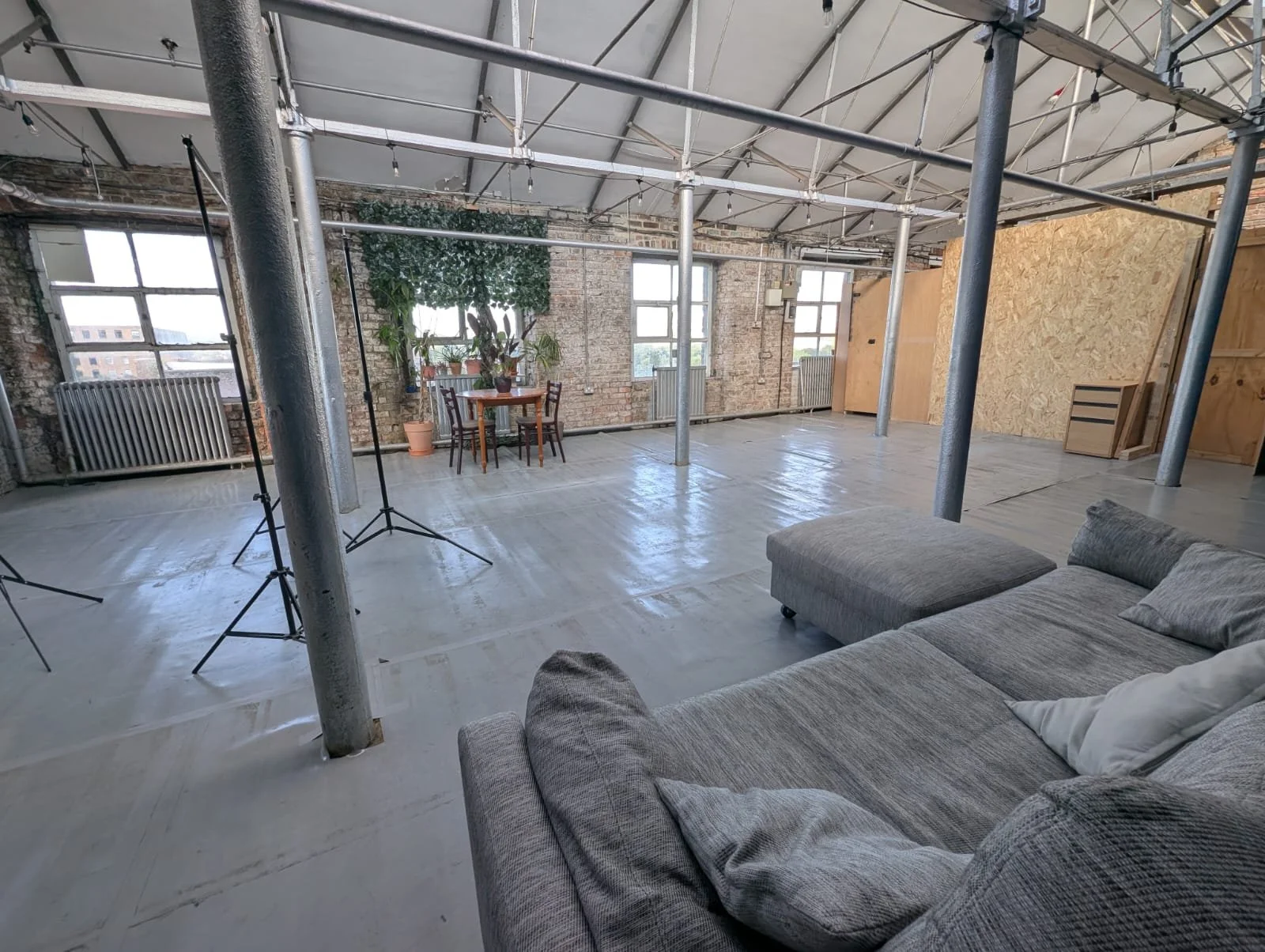 An image of an open studio space with a grey sofa