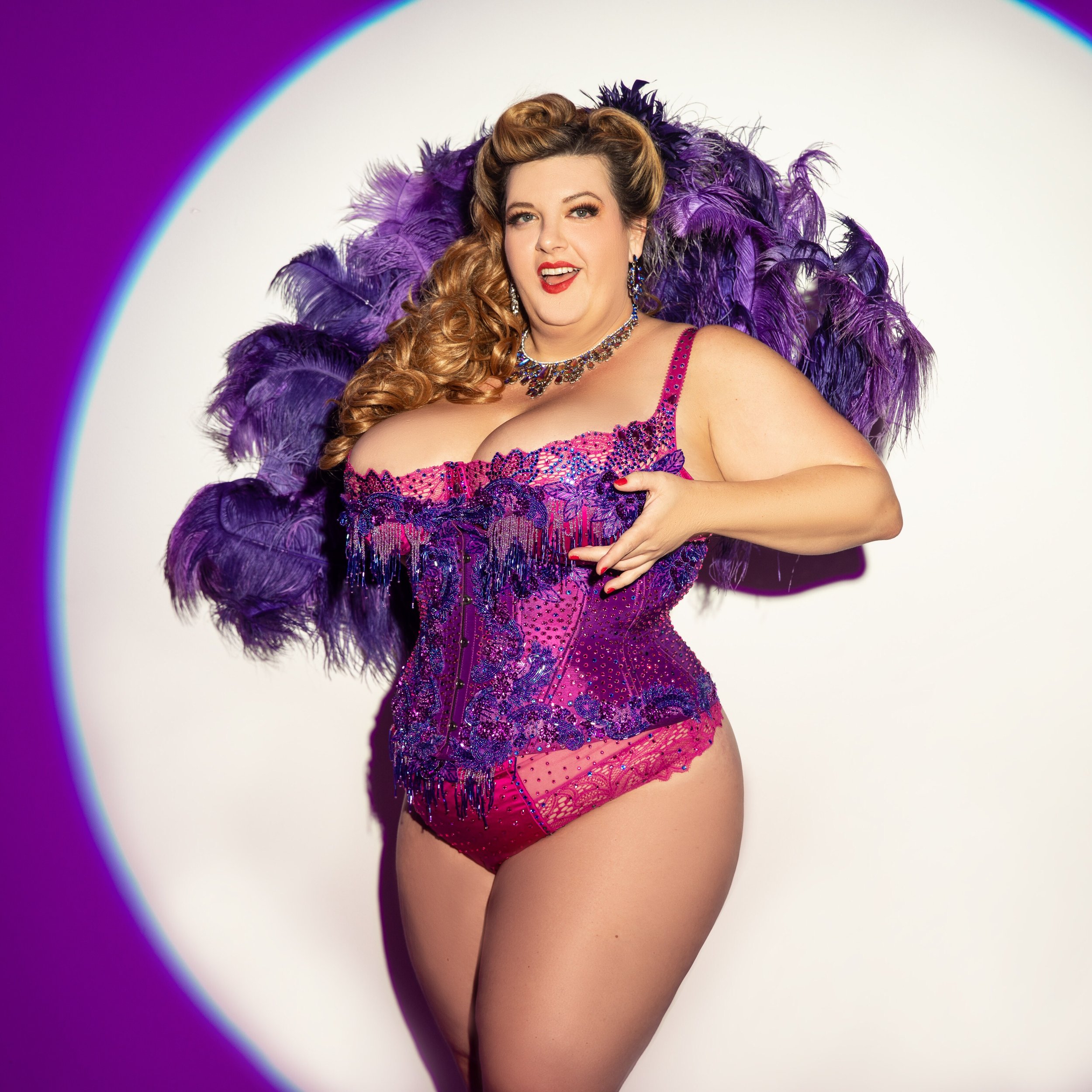 Jezebel Expres, a curvy fair-skinned performer with their hair in ringlets. 