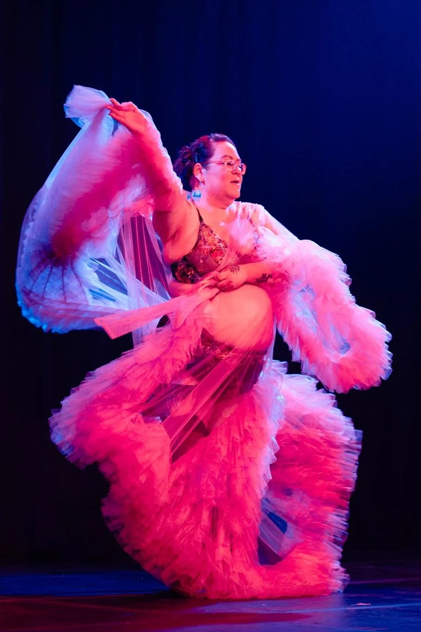 Madame Ode'miin Surprise dances wearing a frilly pink robe
