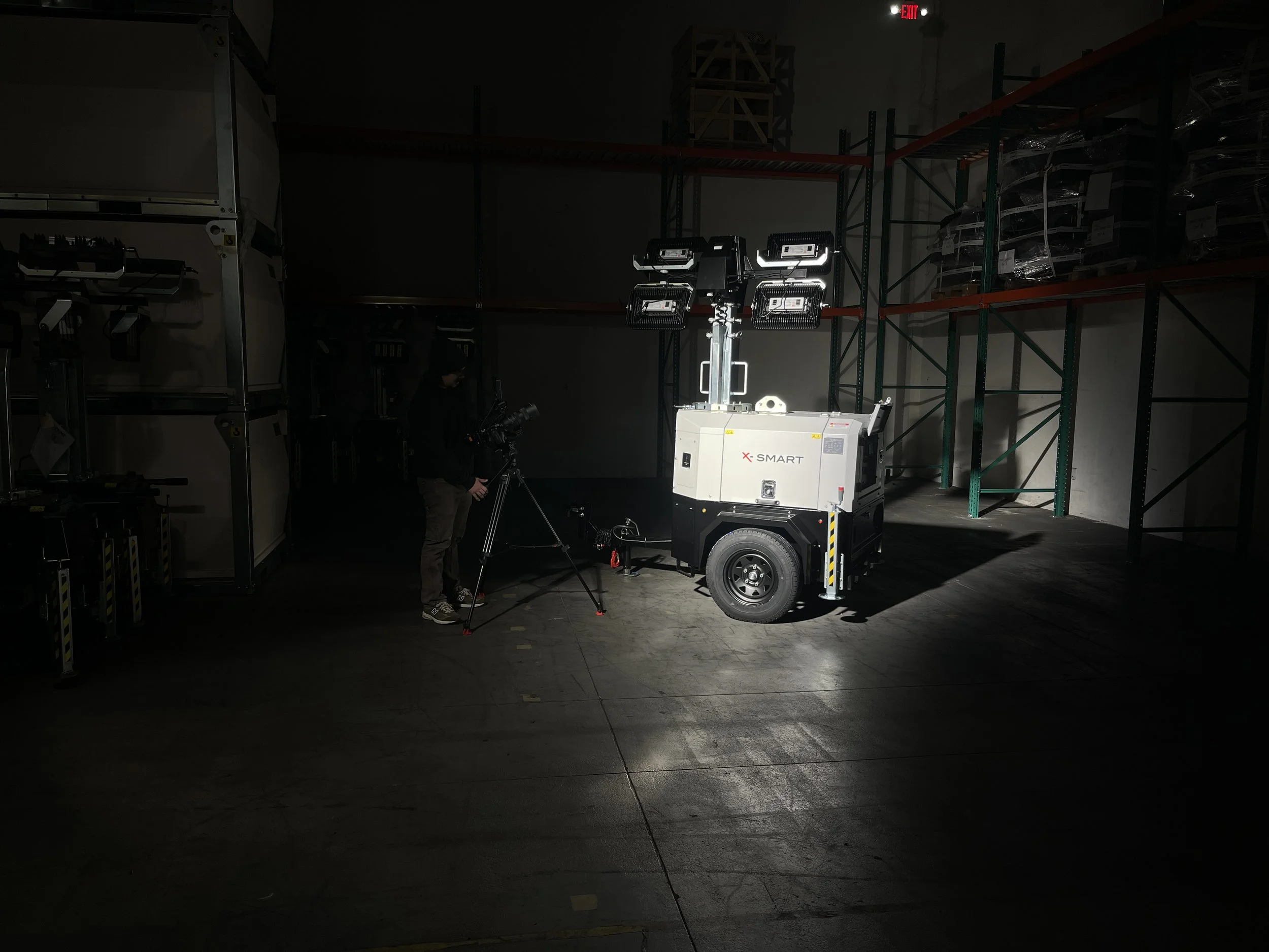 A technician operating a mobile camera truck with bright working lights inside a dark warehouse or storage facility.
