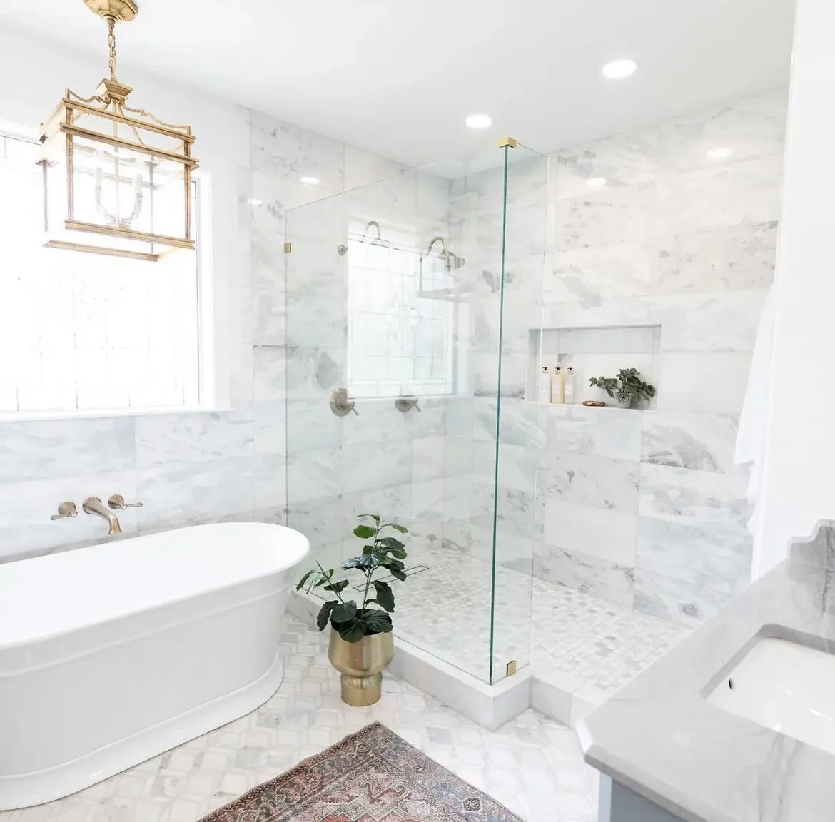 remodeled bathroom with white marble tile and a free-standing tub