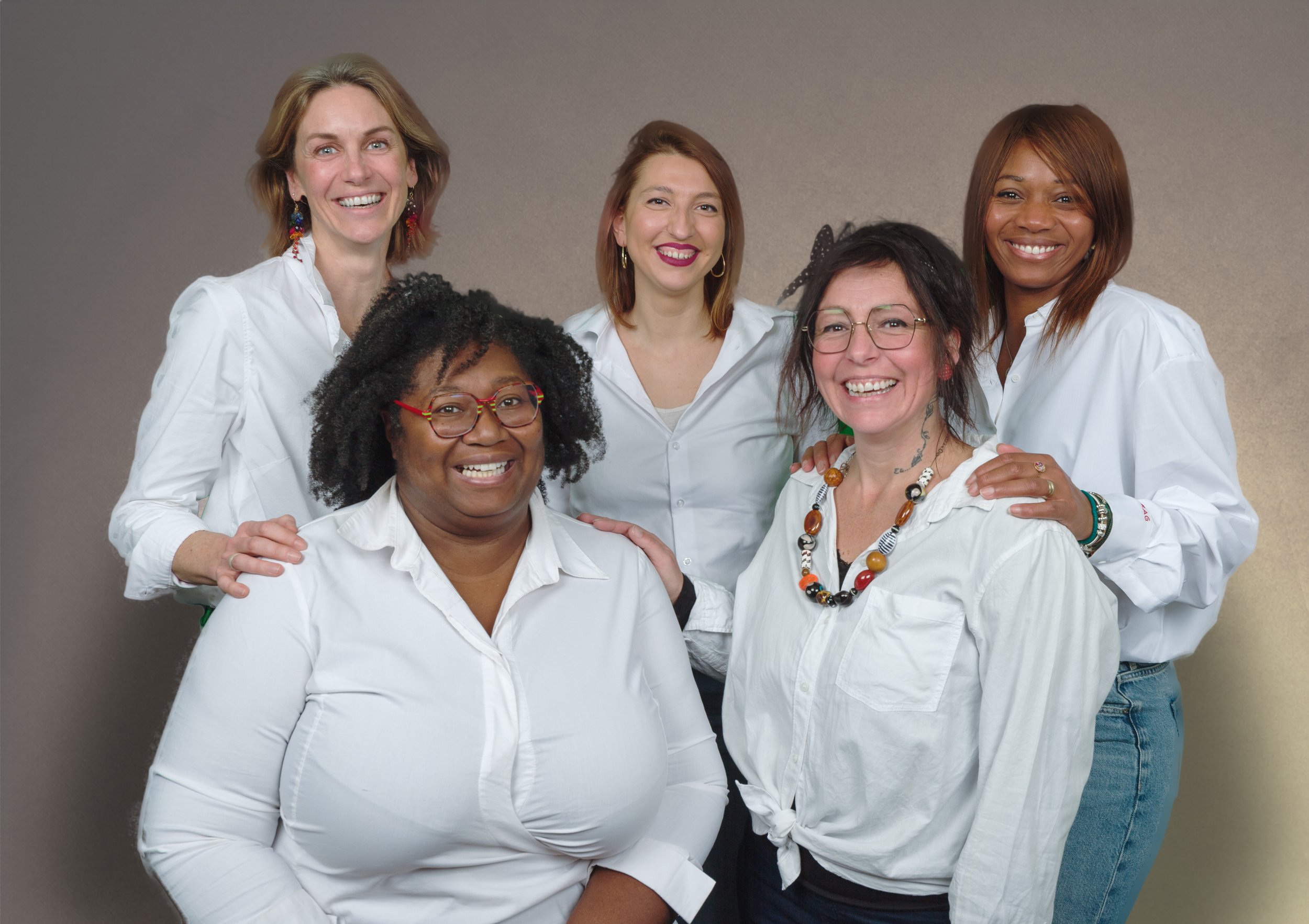 Groupe de six femmes souriantes portant des chemises blanches, posant devant un fond neutre.