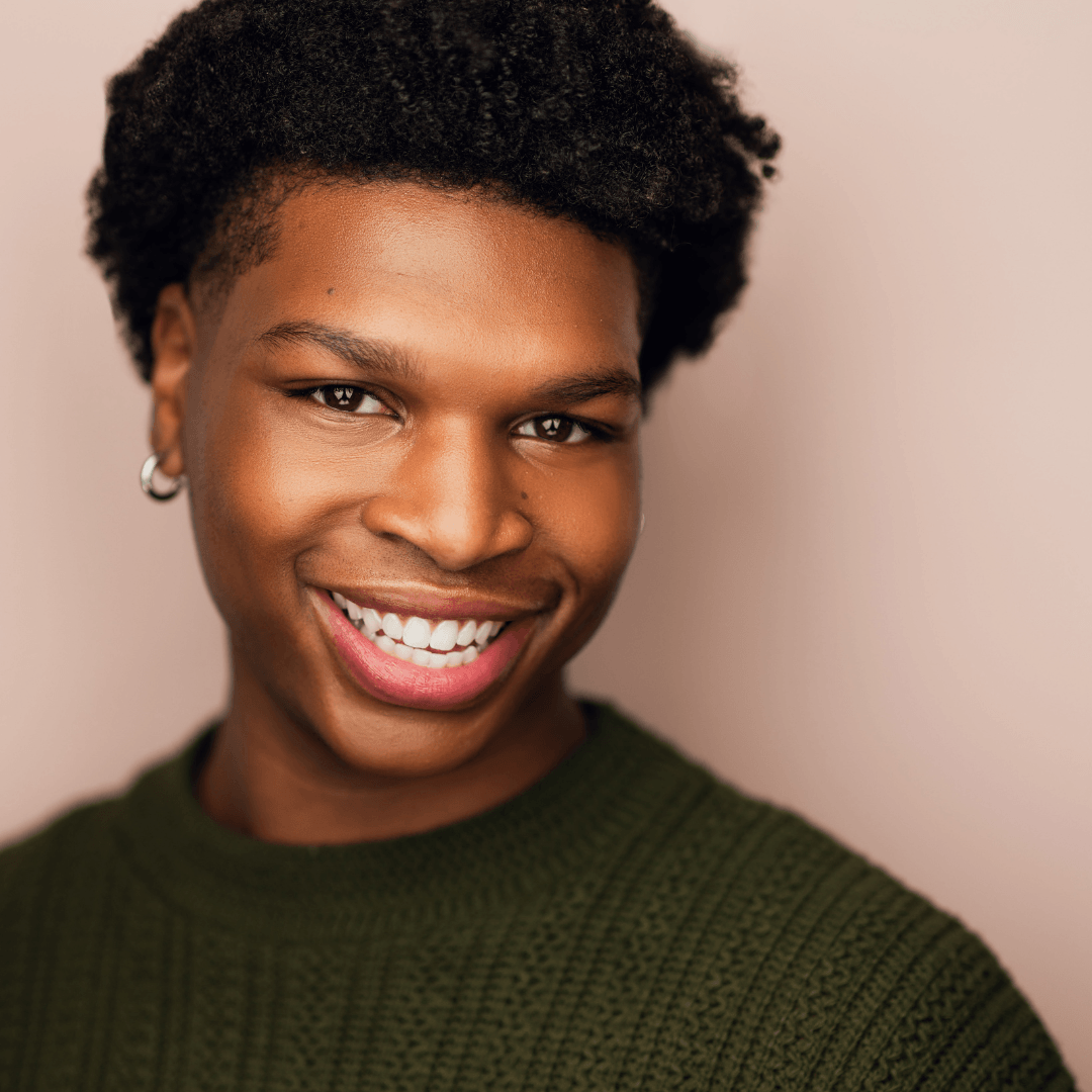 Headshot of a smiling young man wearing a dark green sweater