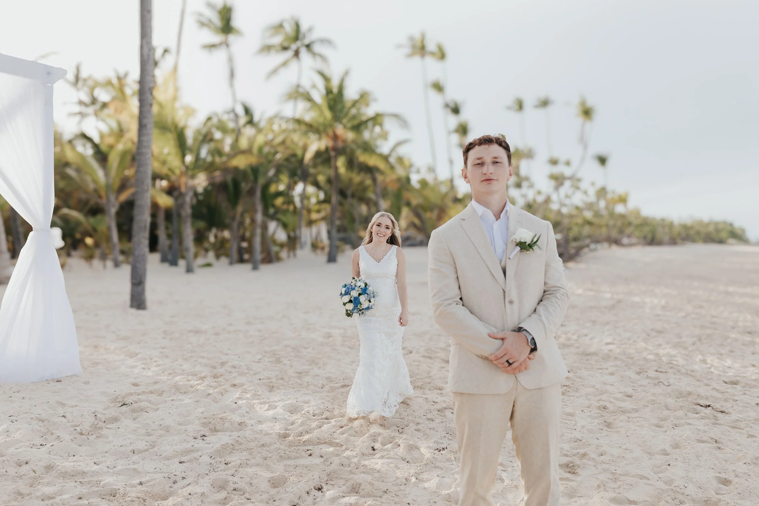 Groom waiting on the beach as bride approaches for first look at Riu Punta Cana