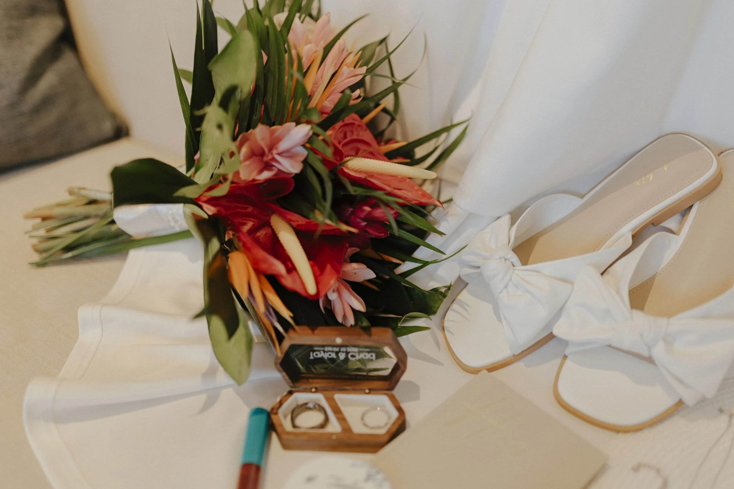 Tropical wedding bouquet, wedding rings, and bridal shoes styled together in a flat lay at Secrets Tides