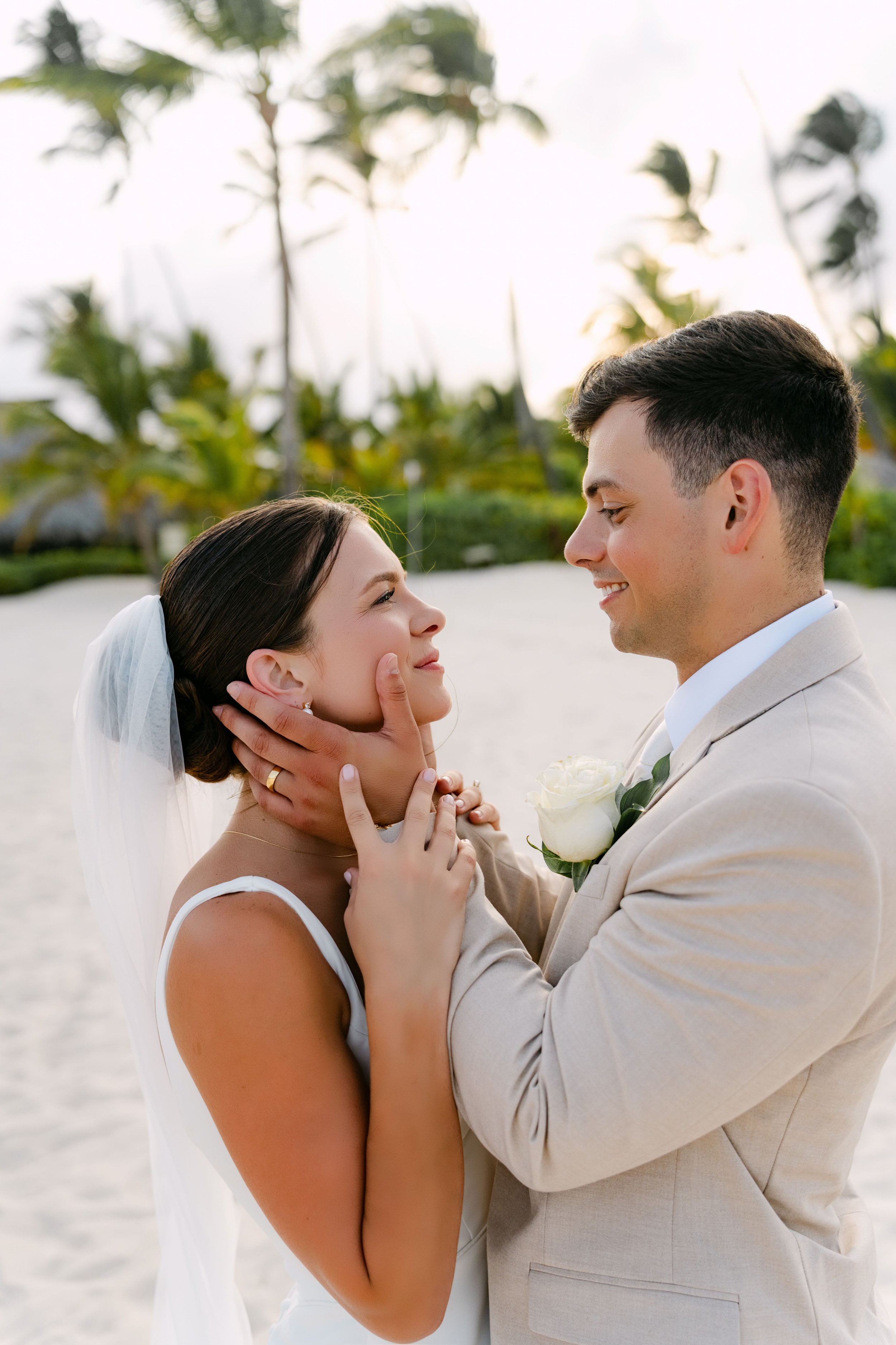 Groom holding bride's face, both smiling, Dreams Royal Beach Punta Cana wedding portrait.