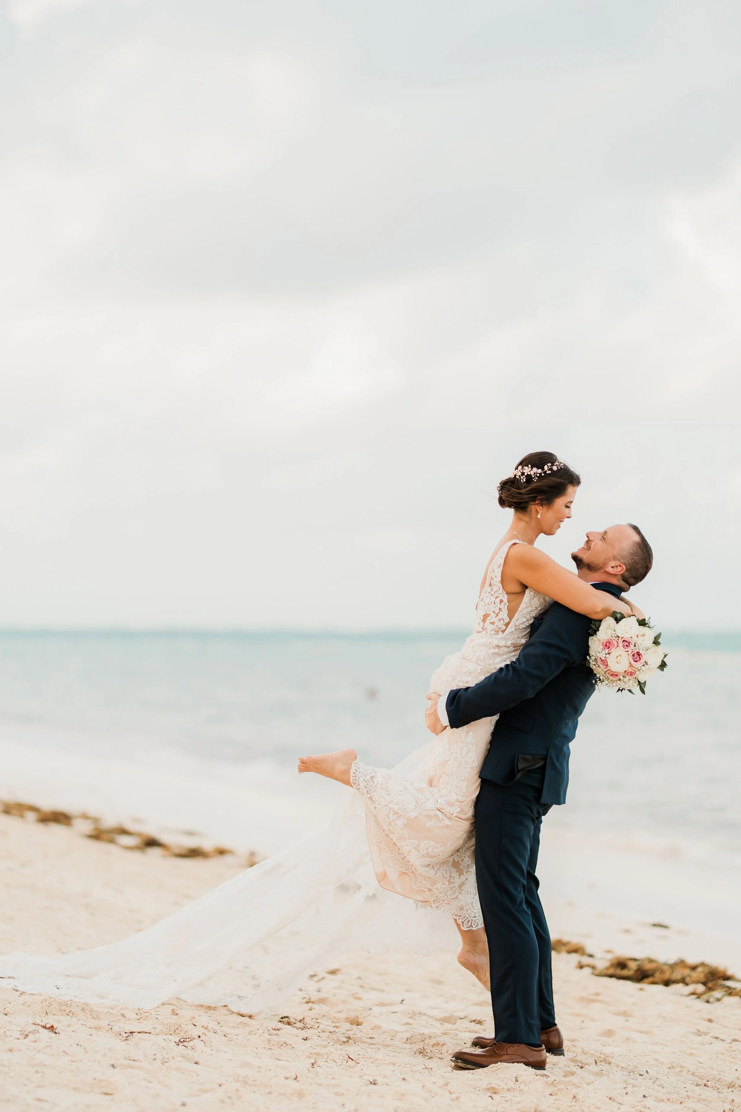 Groom lifting bride playfully on the beach during golden light portraits at Dreams Flora
