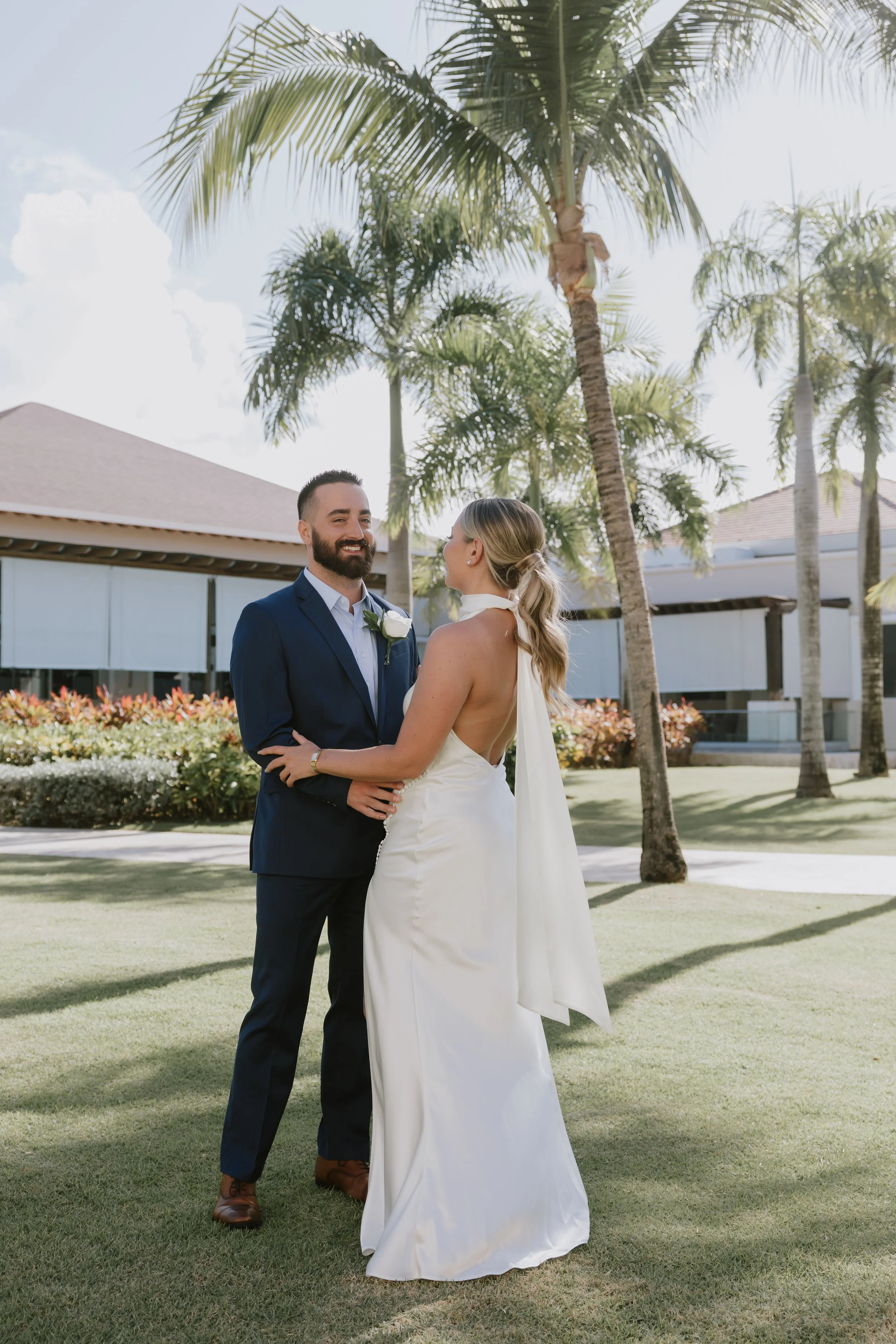 Bride and groom smiling at each other during portraits on the lawn at Dreams Royal Beach
