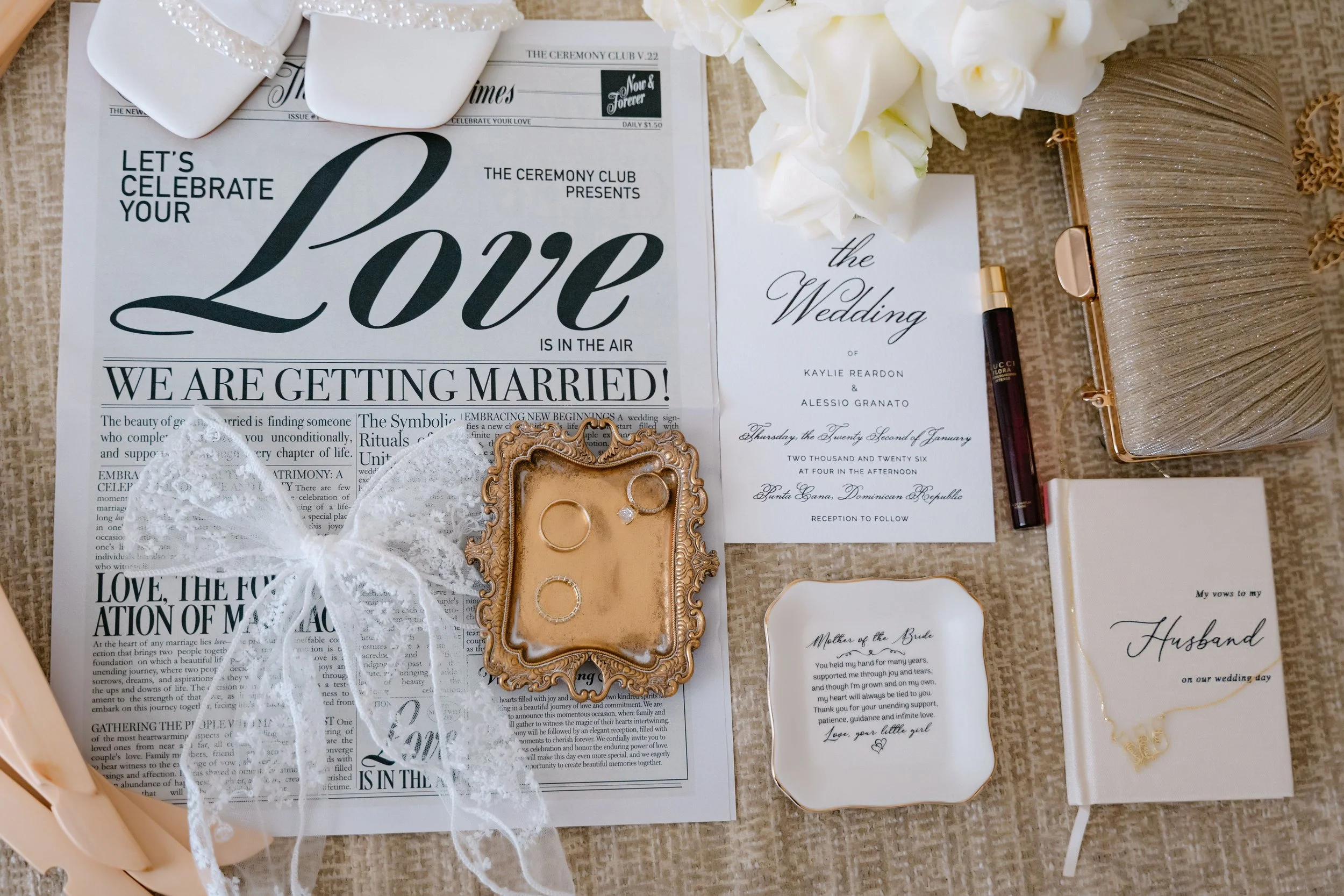 Elegant white and gold wedding flat lay with a newspaper-style invitation and vow book at a Majestic Punta Cana wedding