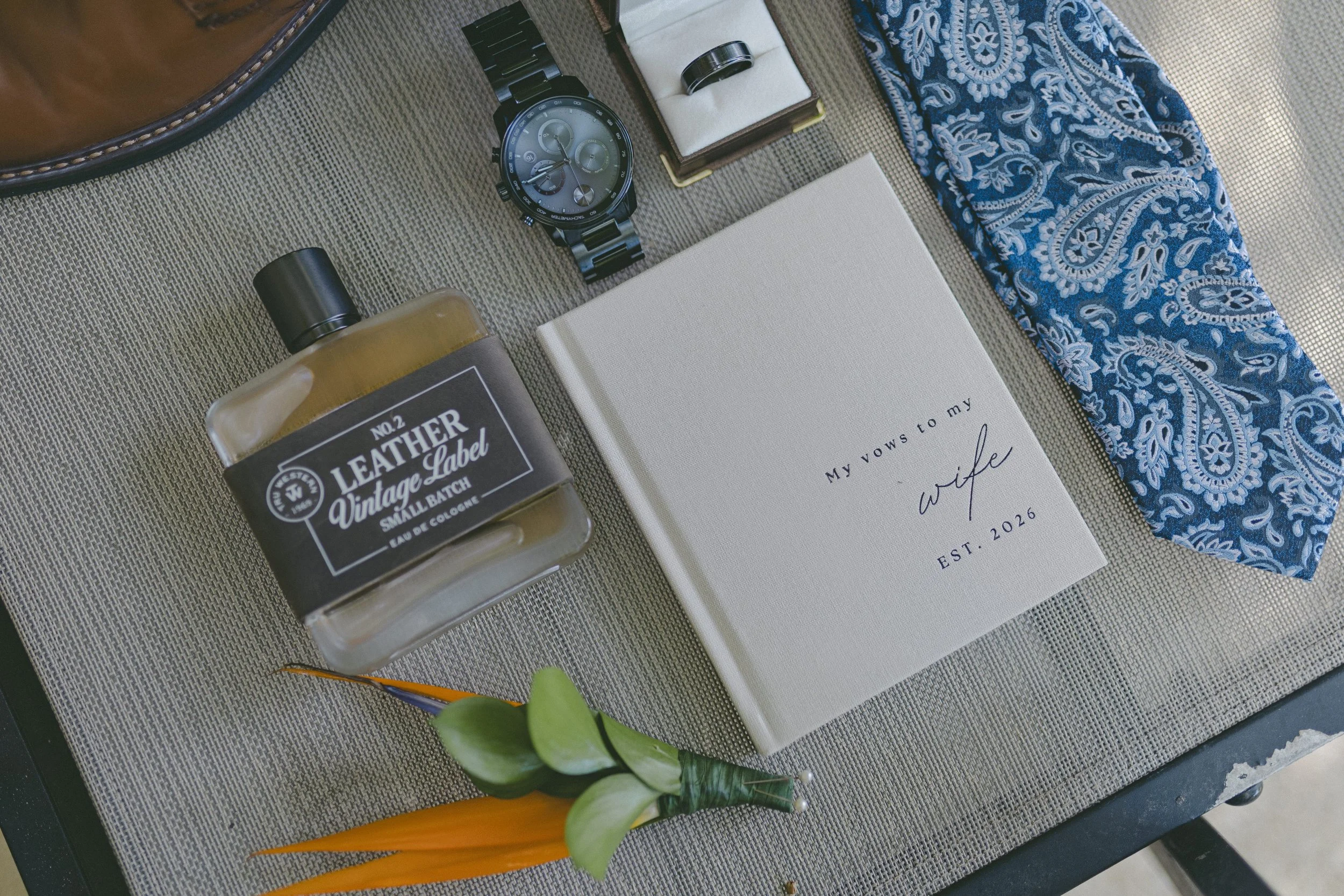 Groom's wedding details flat lay with watch, cologne, and vows book at Dreams Royal Beach