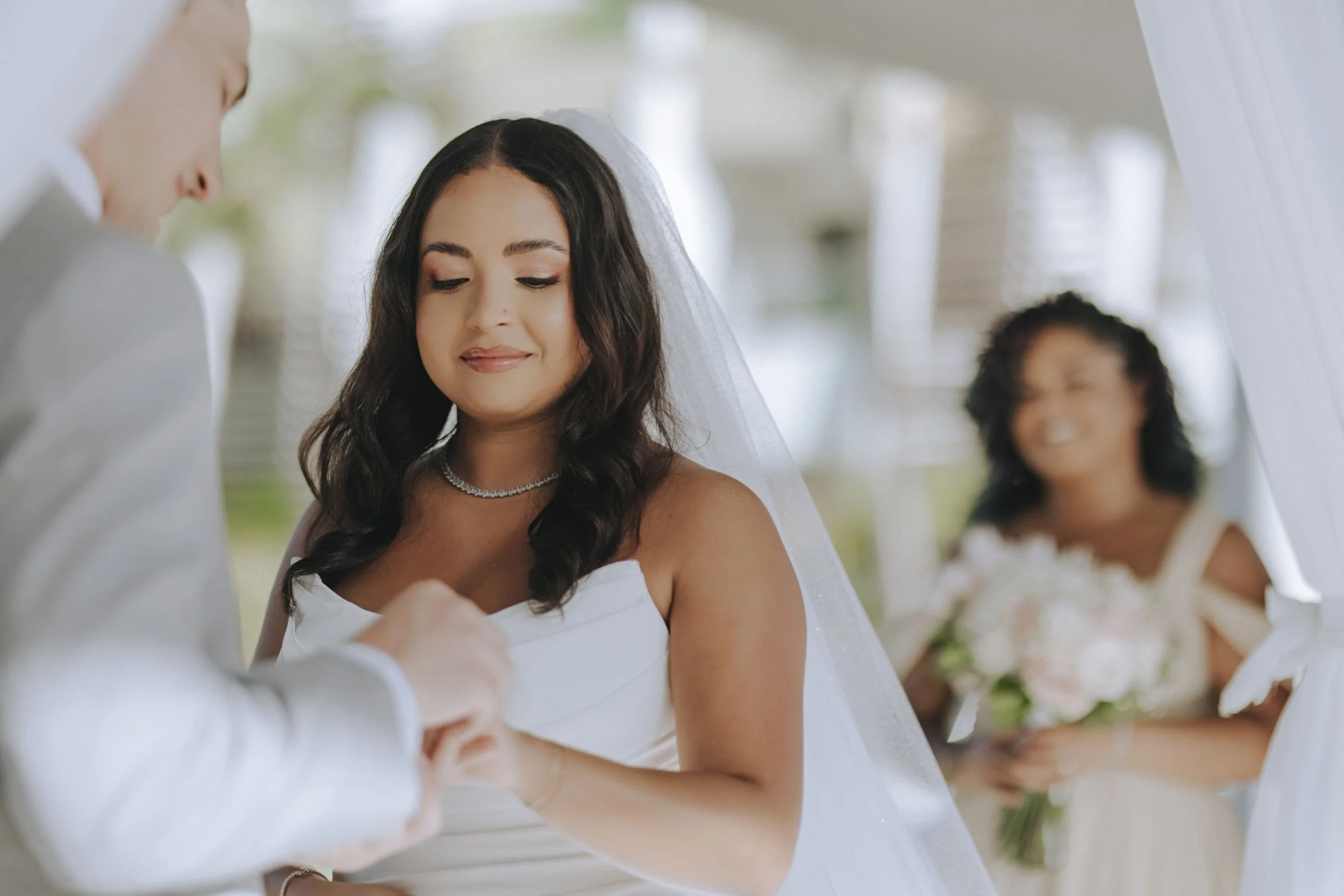 Bride smiling softly while holding groom's hand during the vow exchange at Dreams Onyx