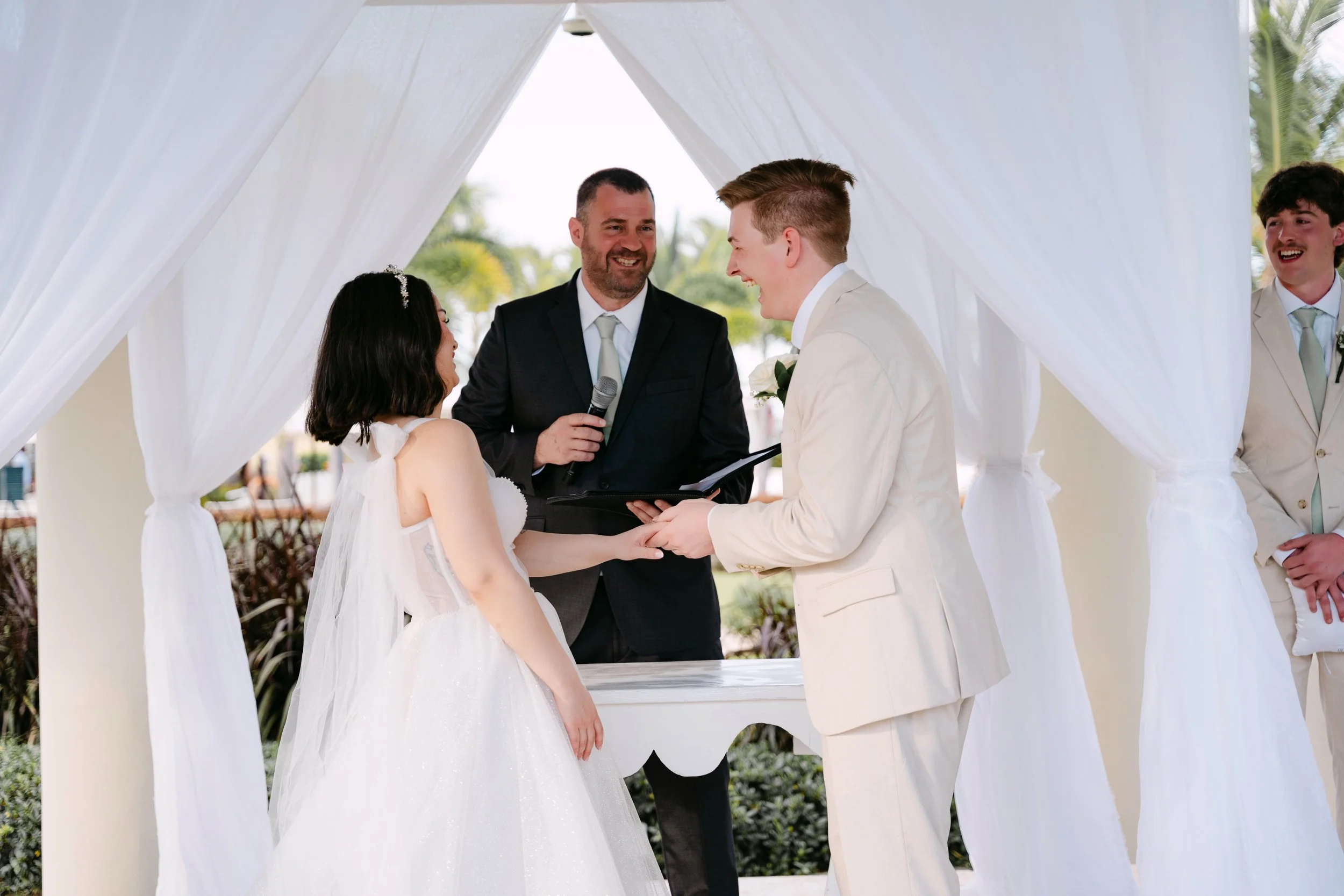 Bride and groom exchanging vows under a modern gazebo beside a reflecting pool at Dreams Onyx