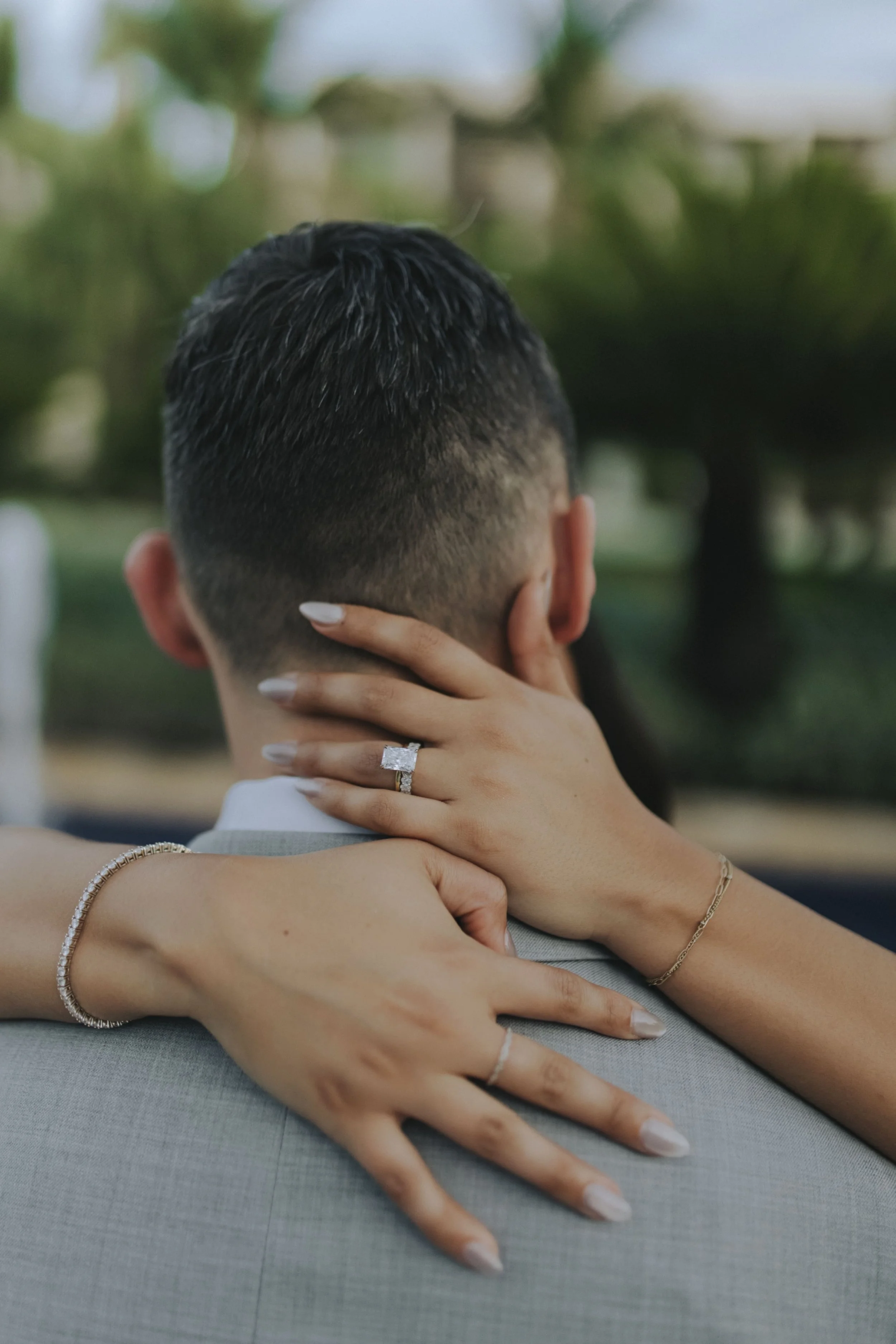 Close-up of bride's hand and engagement ring resting on groom's shoulder during a portrait embrace at Dreams Onyx