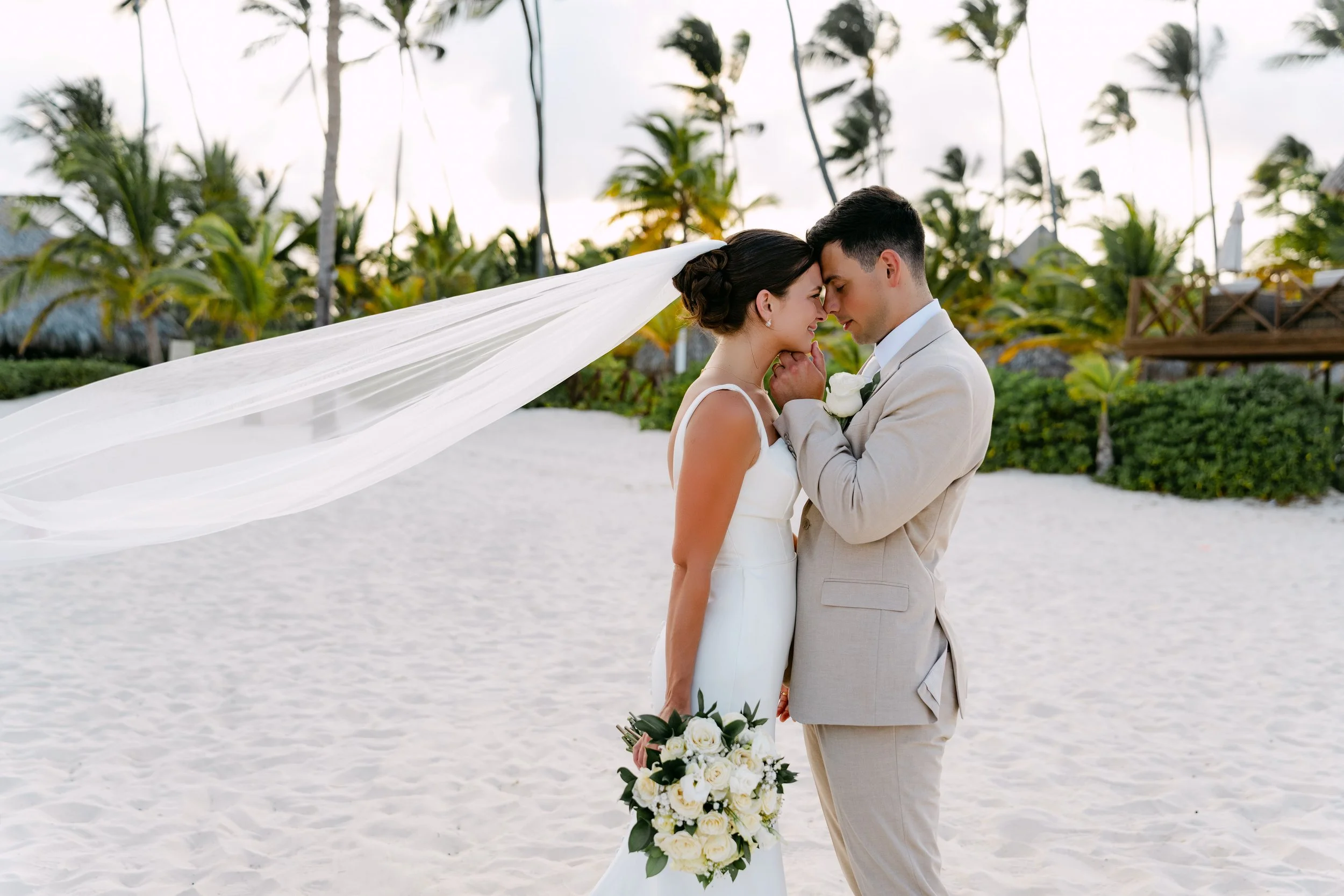 Bride and groom walking on the beach with veil flowing in the wind, Dreams Royal Beach Punta Cana wedding.