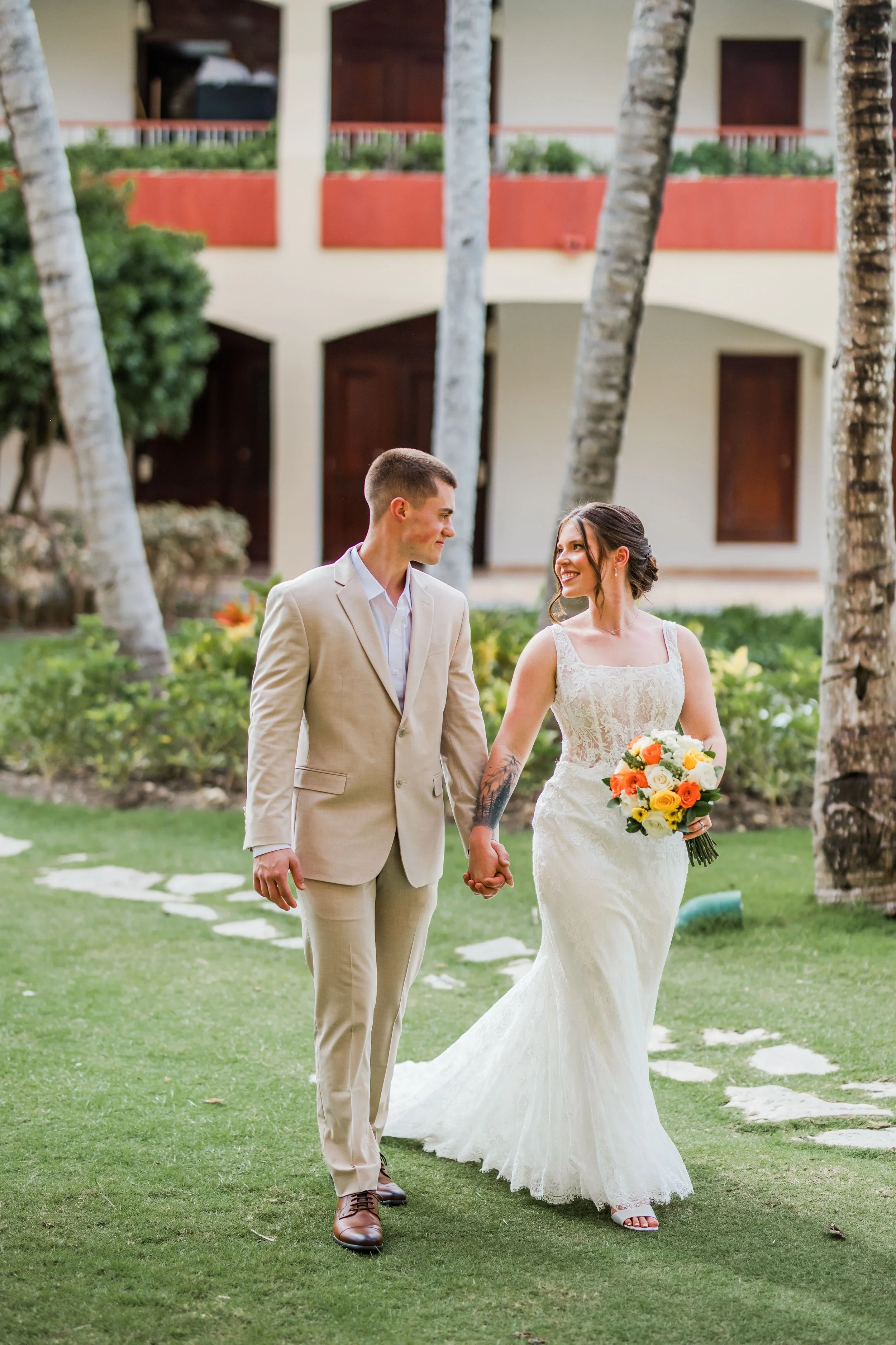 Bride and groom walking hand in hand through the gardens at Majestic Colonial