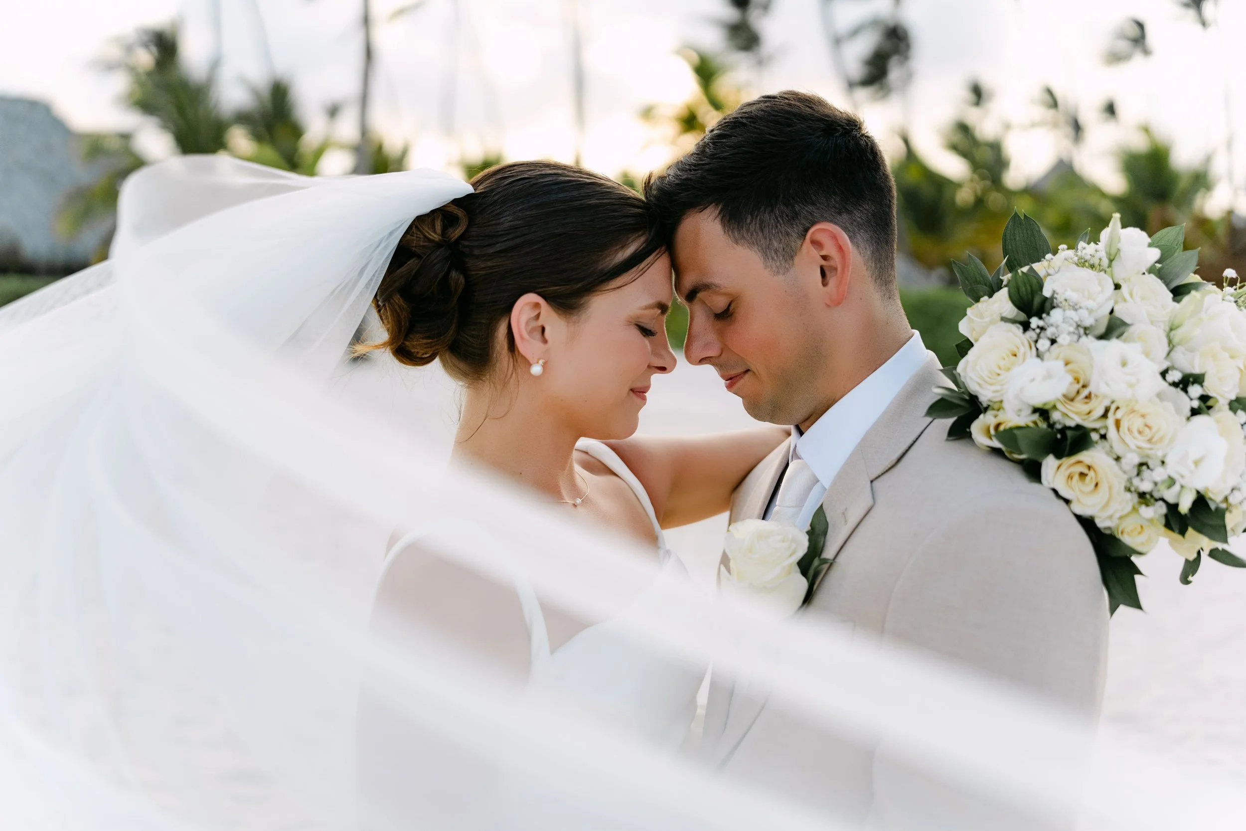 Bride and groom forehead to forehead under a flowing veil, real wedding at Dreams Punta Cana by WBA Studio.