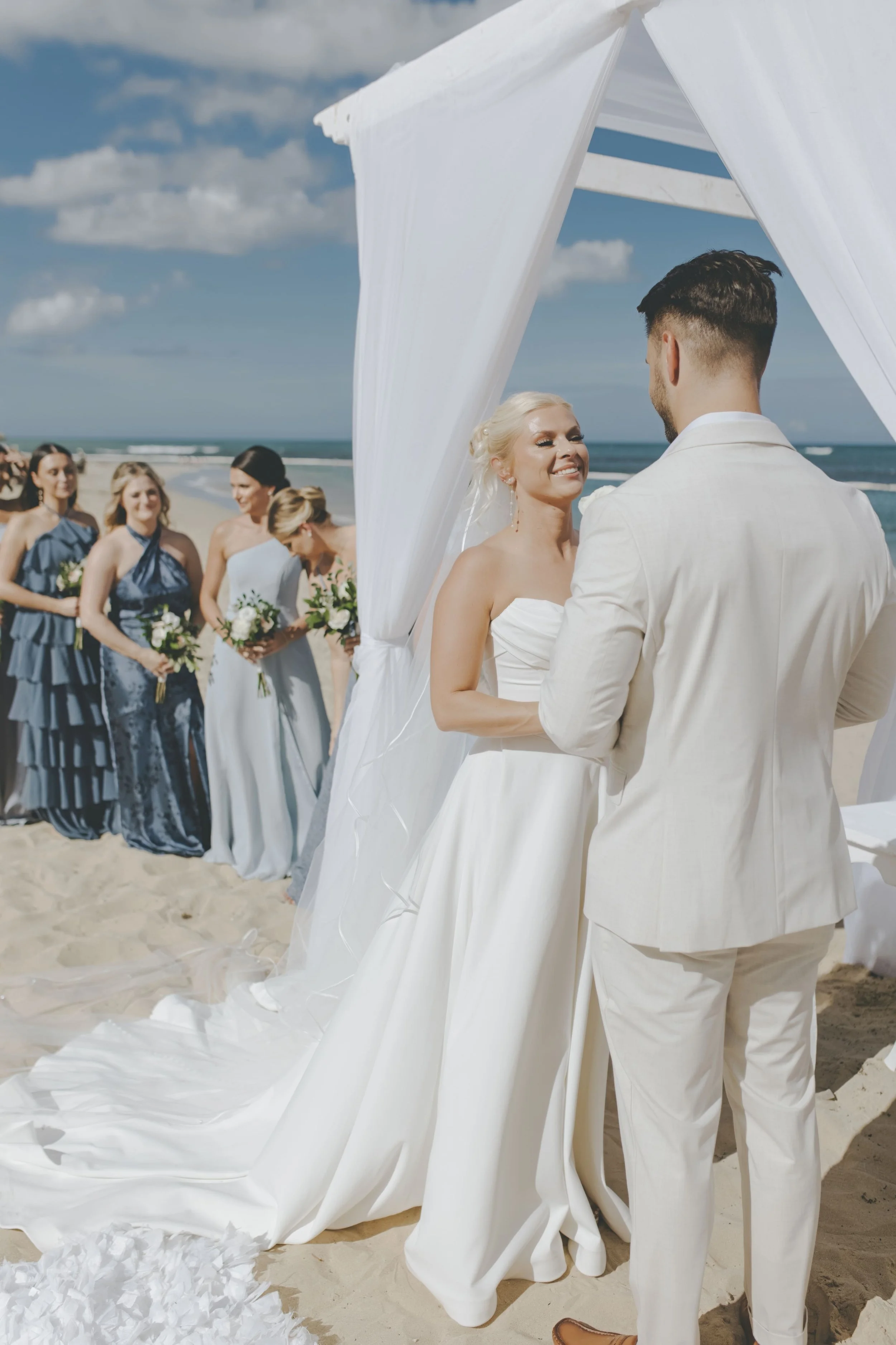 Bride and groom at their beach ceremony with bridesmaids in blue at a Punta Cana destination wedding