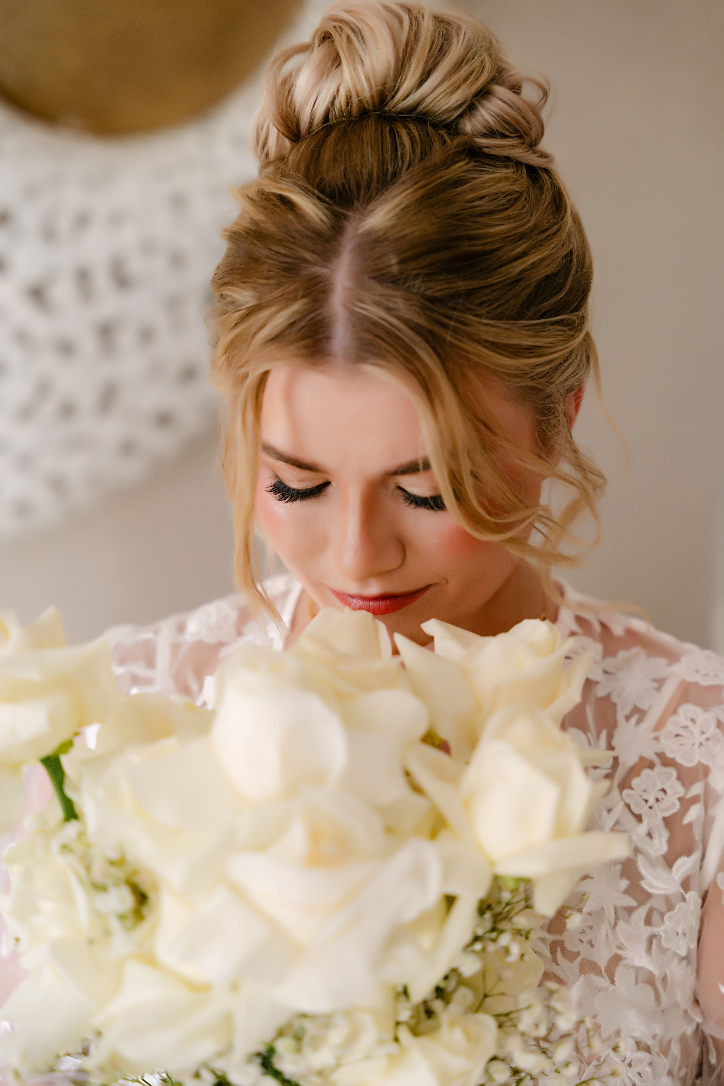 Bride in a lace gown looking down at her white rose bouquet before her Majestic wedding in Punta Cana
