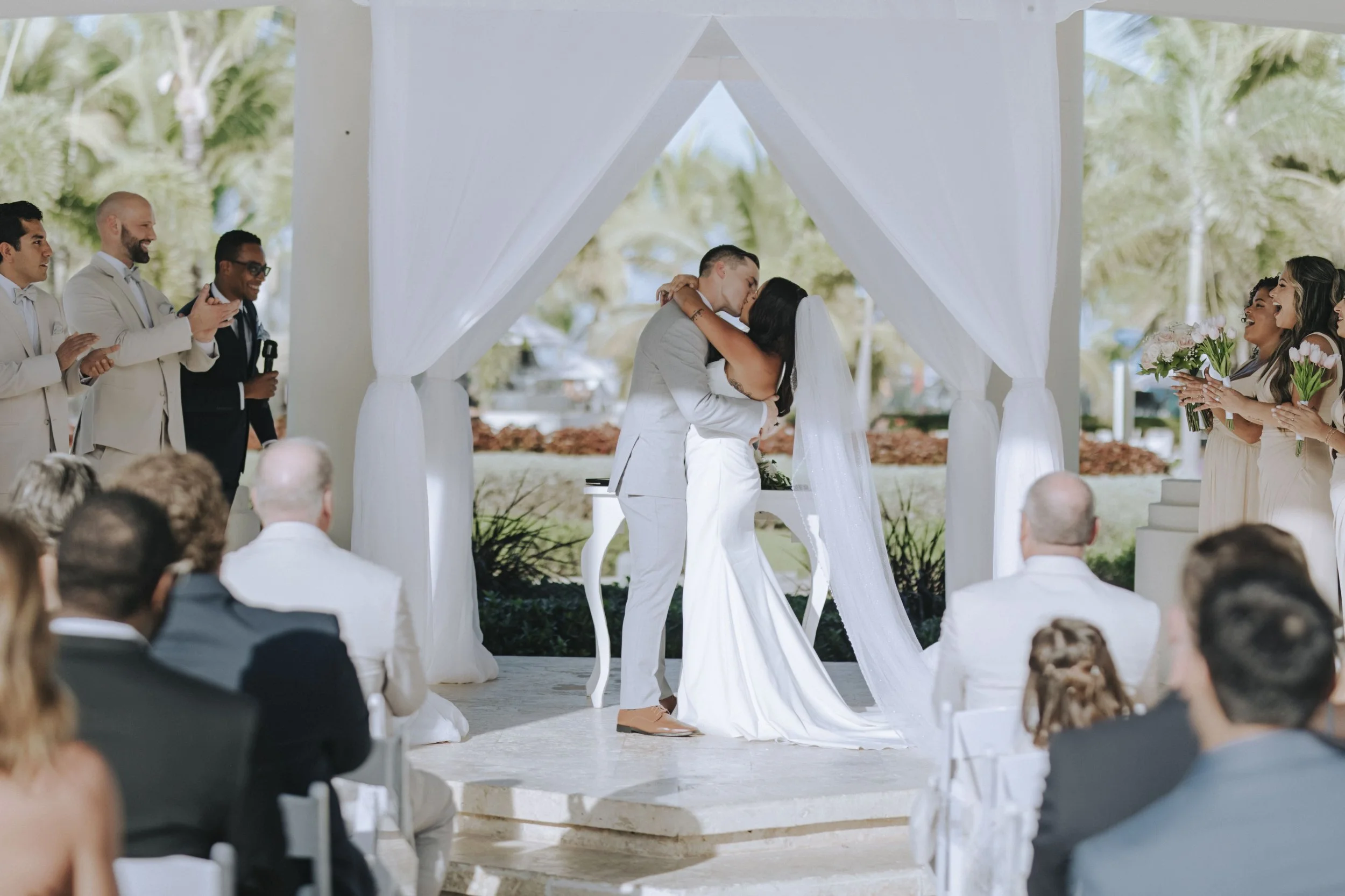 Bride and groom sharing their first kiss under the modern white ceremony pavilion at Dreams Onyx