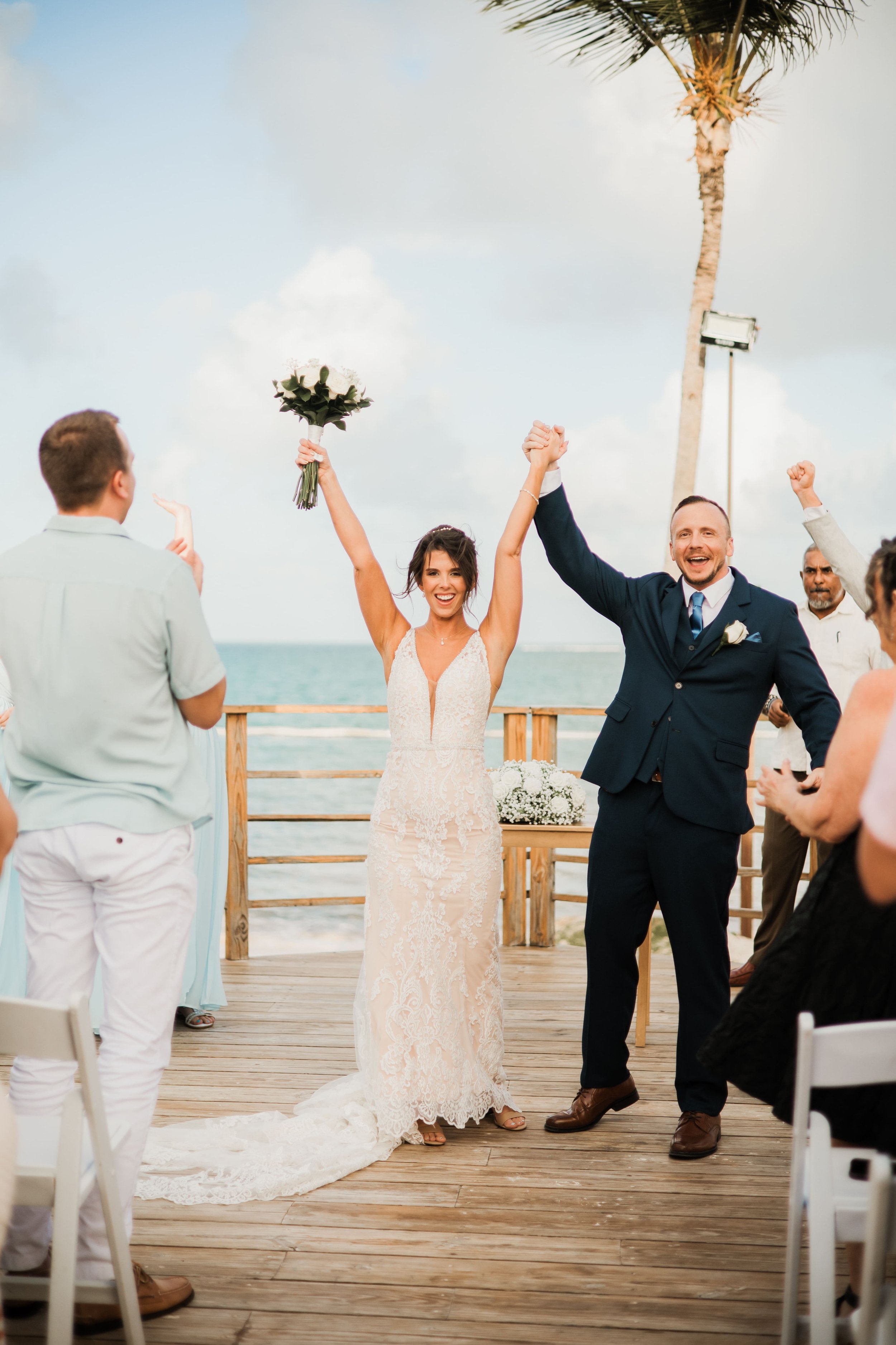 Bride and groom raising hands in celebration after their pier ceremony at Dreams Flora