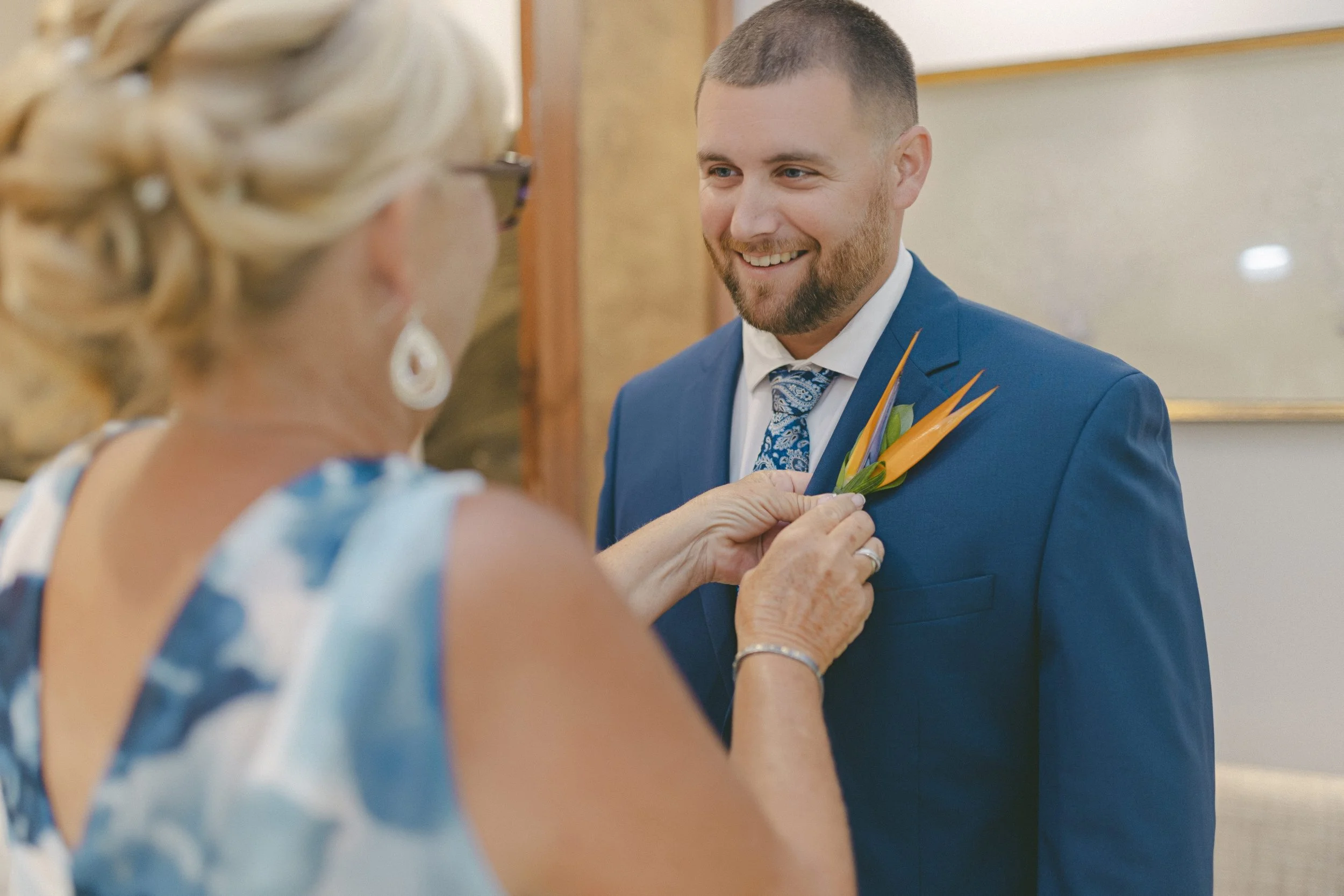 Groom's mother pinning boutonniere before Dreams Royal Beach wedding ceremony