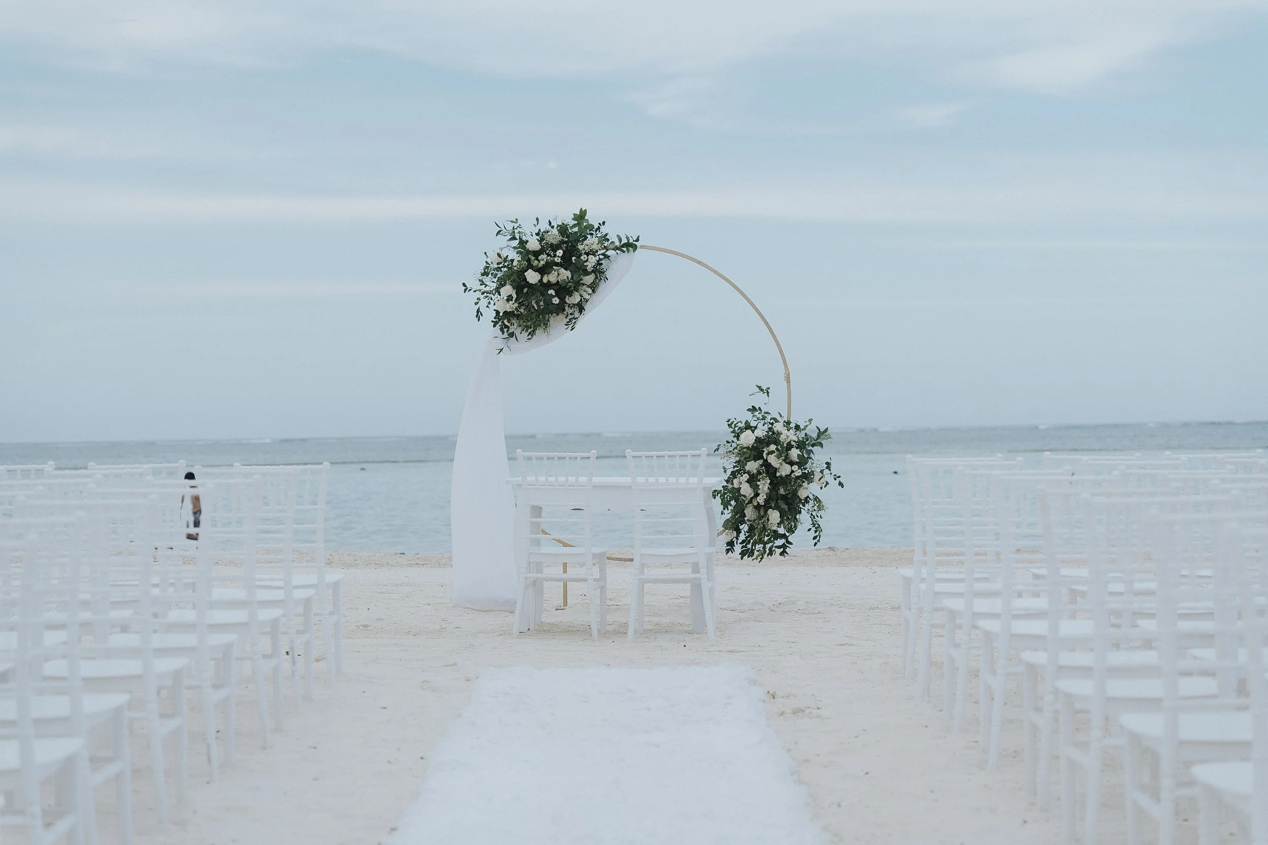 The gold hoop ceremony arch set up on the beach at Serenade Punta Cana, ocean behind