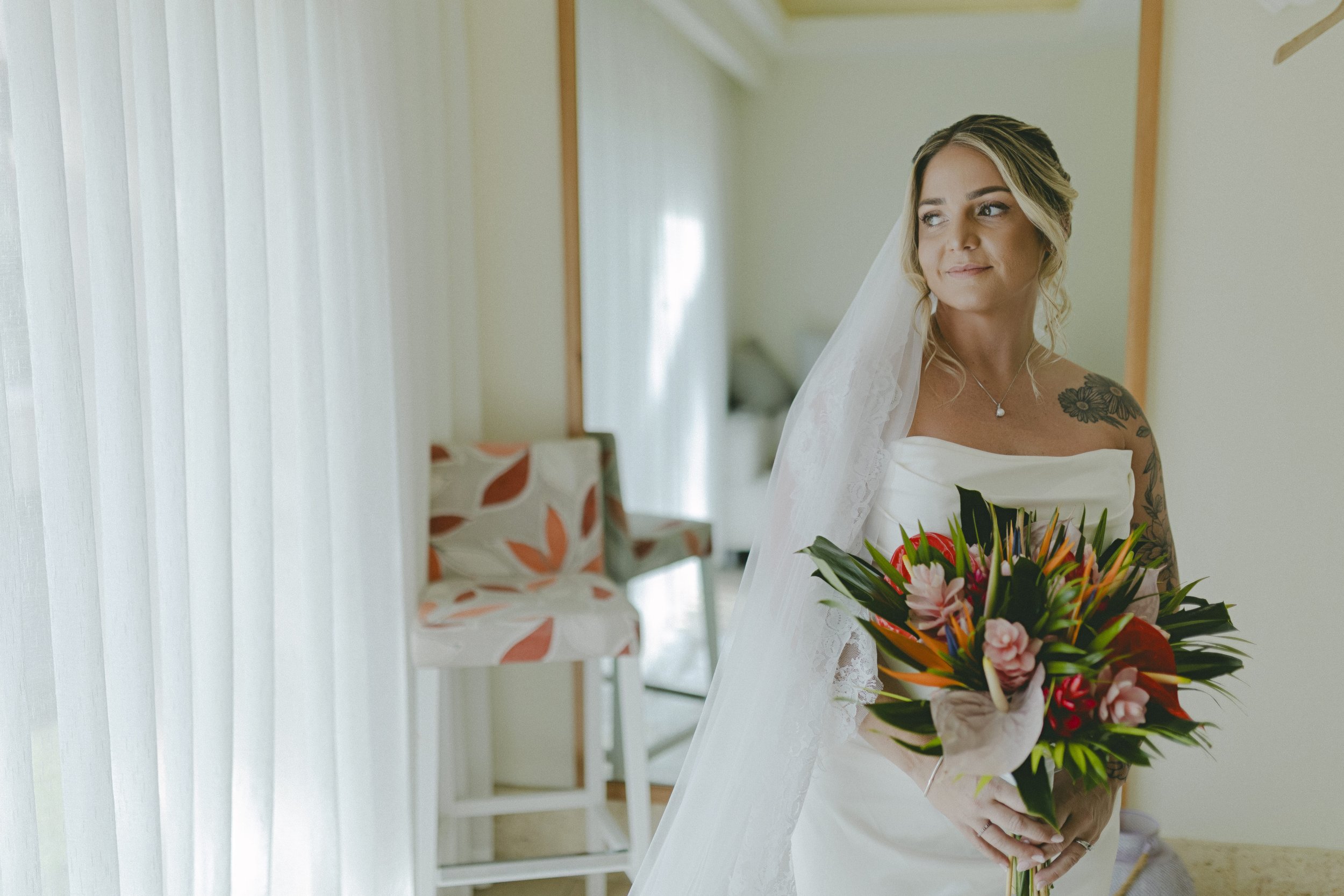 Bride standing by window with bouquet before Dreams Royal Beach wedding