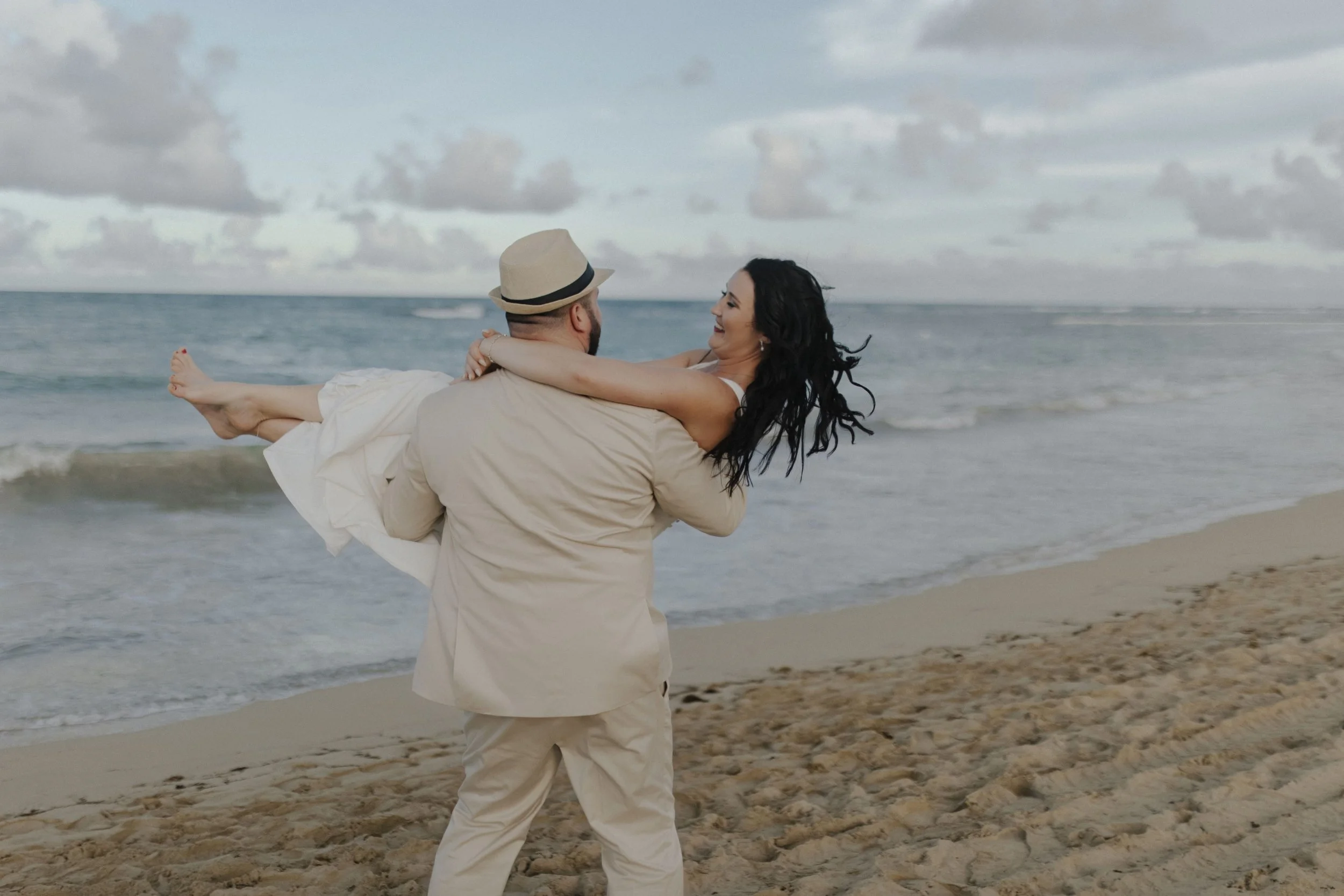 Groom carrying bride along the shoreline during golden hour portraits at a Secrets Tides wedding