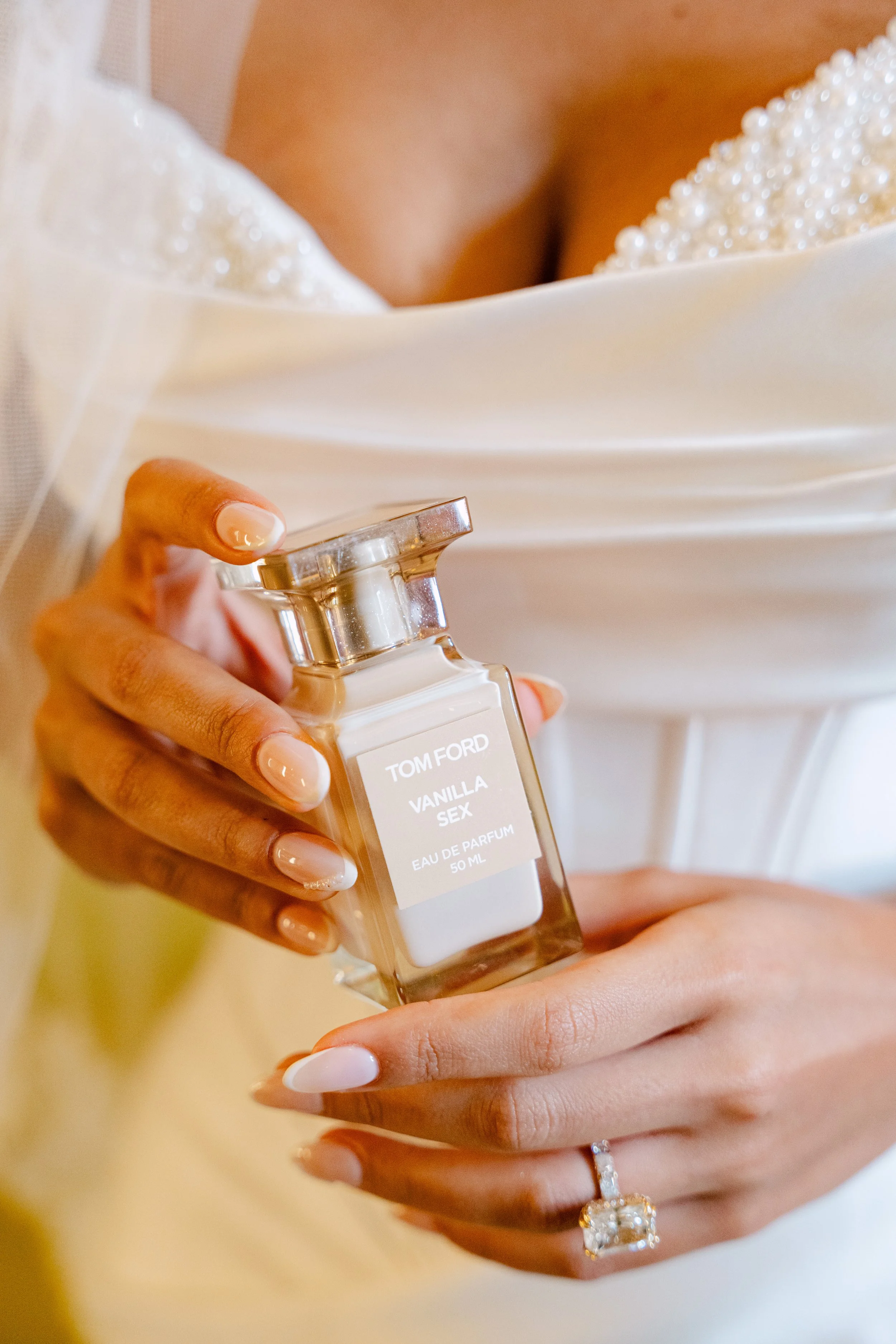 Bride holding a perfume bottle while getting ready in her wedding dress