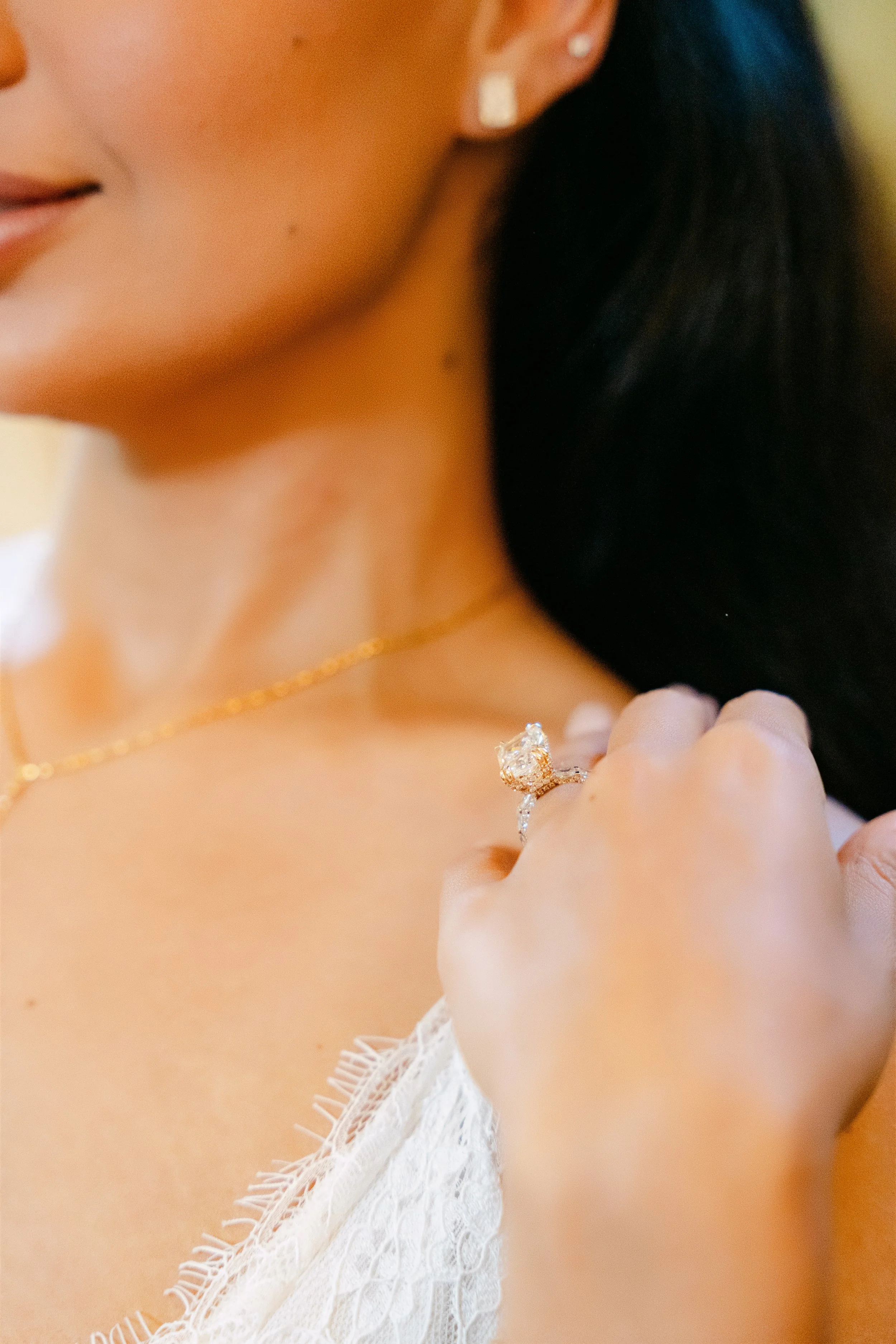 Close-up of the bride’s delicate gold necklace and engagement ring on her wedding day