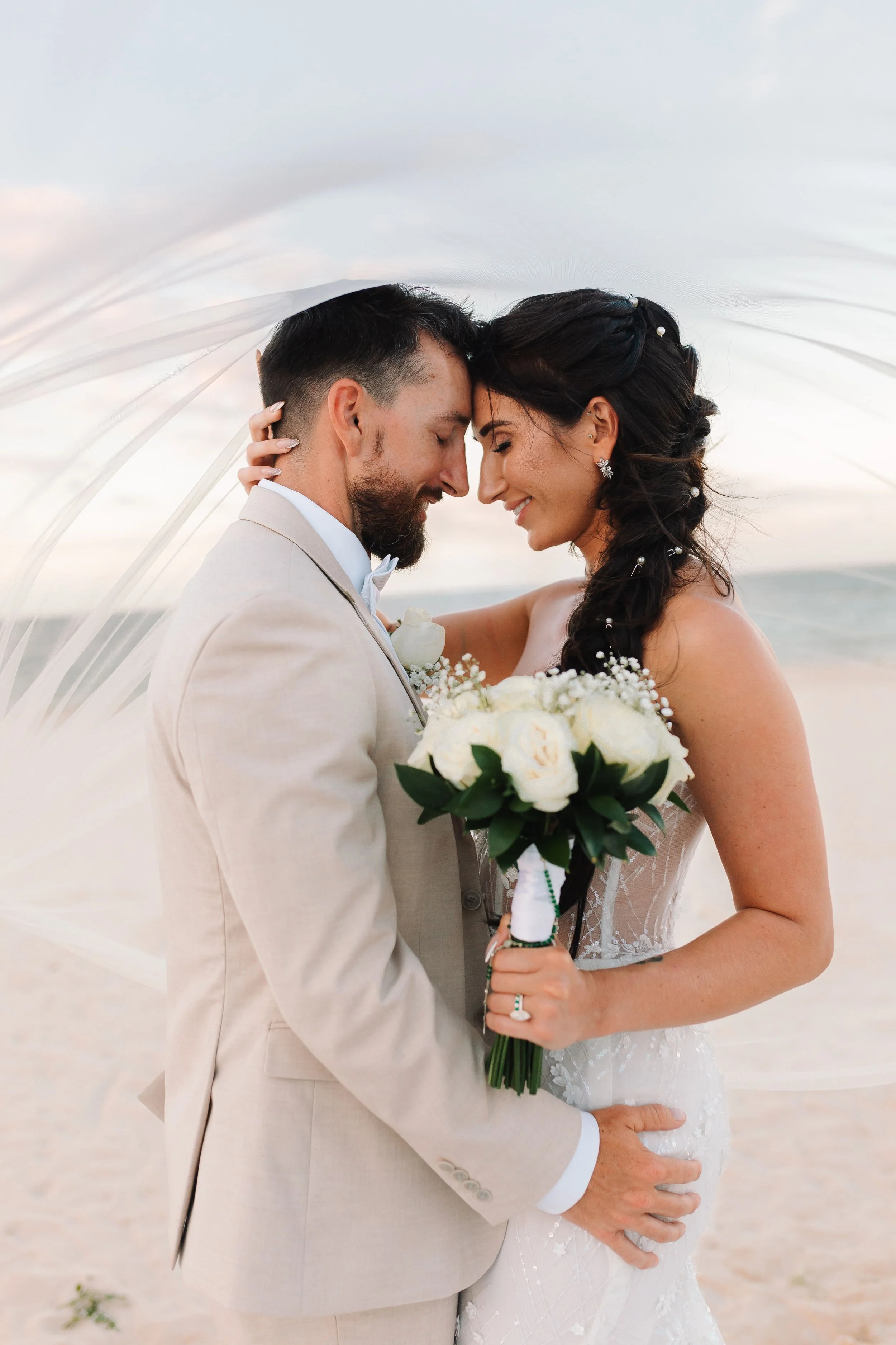 Bride and groom sharing an intimate moment under her veil at Secrets Royal Beach
