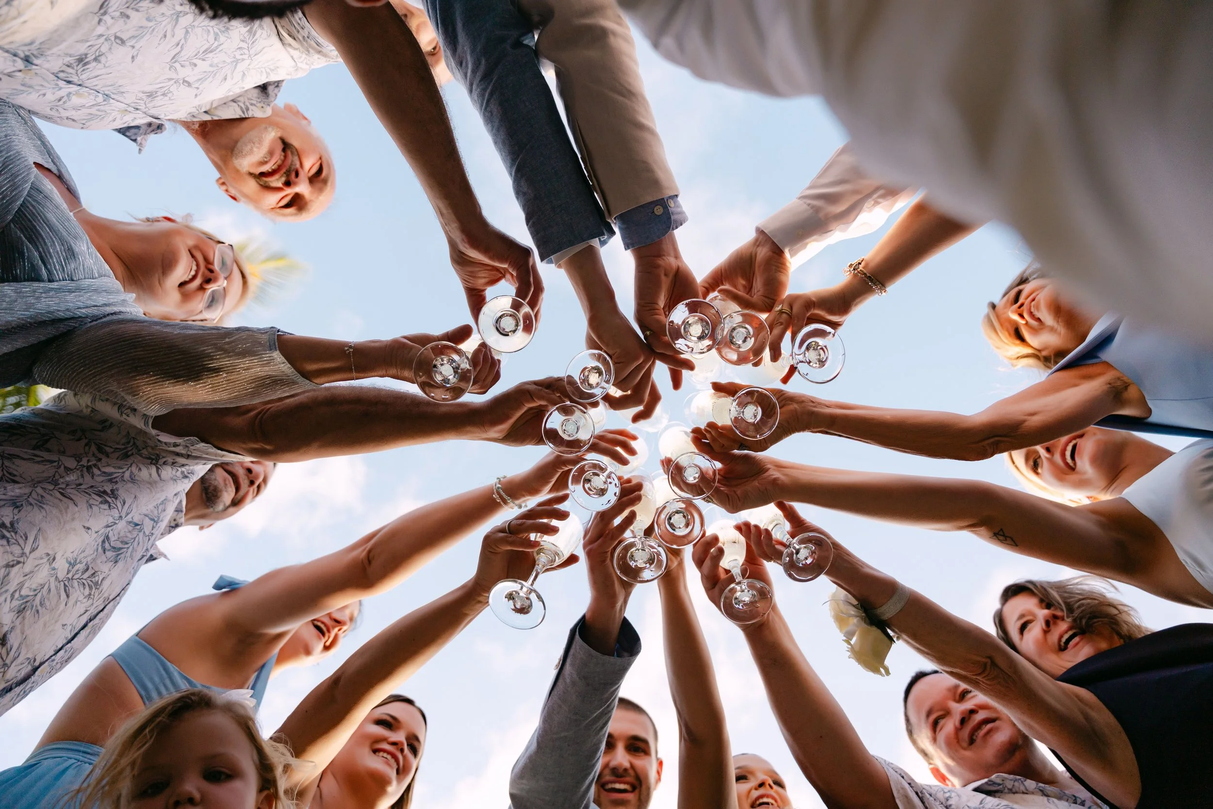 Overhead shot of wedding guests raising champagne glasses in a circle toast at Dreams Flora