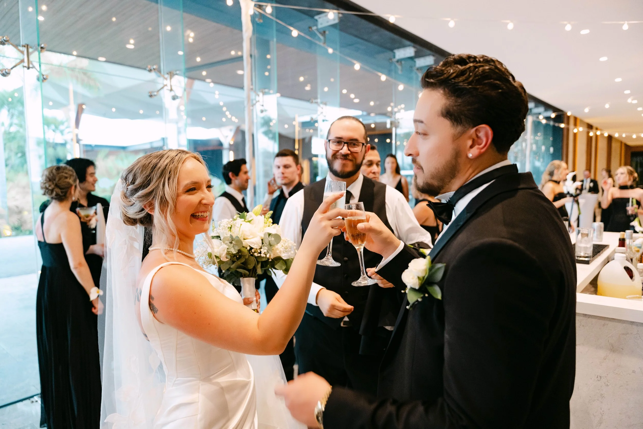 Bride and groom toasting champagne with guests in black-tie attire at their Secrets Tides wedding reception in Punta Cana