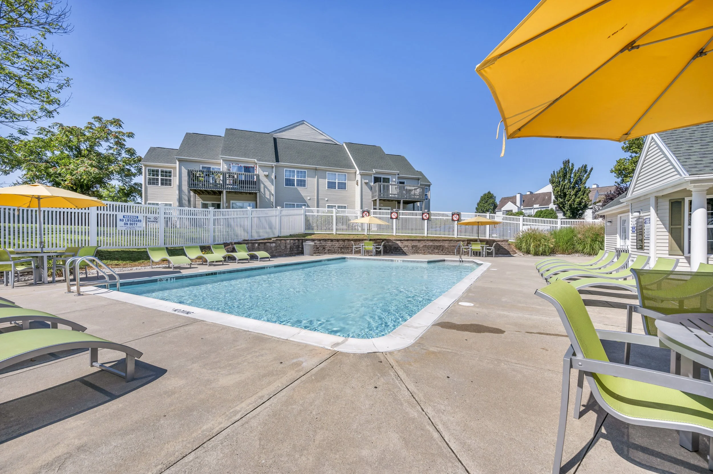 Outdoor resort-style swimming pool with lounge chairs at a pet-friendly apartment community on a sunny day.