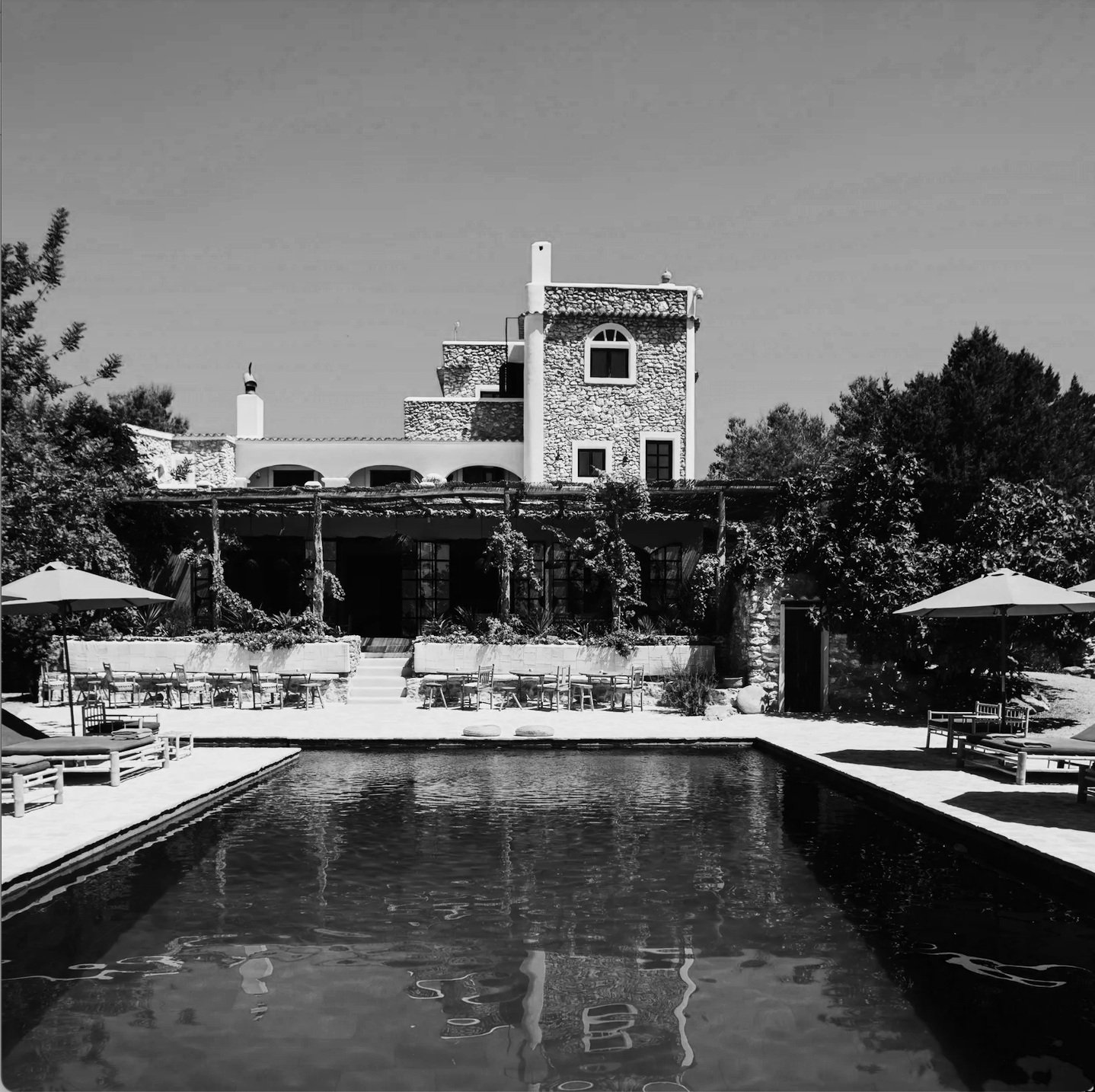 Pool area at La Granja in Ibiza, featuring a serene setting with loungers and views of the countryside.