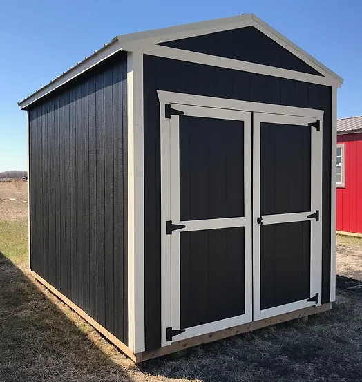 Small black storage shed with white trim and double doors on a grassy area.