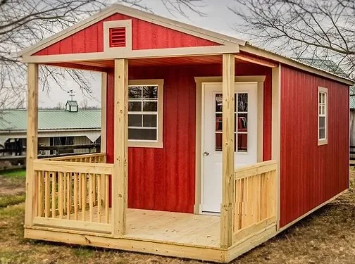 Red wooden shed with porch and white door in a yard