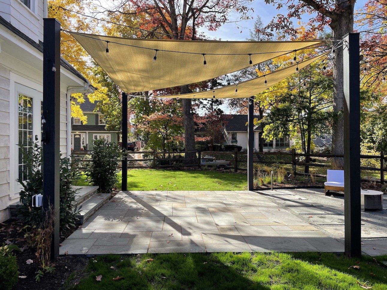 Backyard hardscaping with sail canopy, italian lighting, split rail natural perimiter fence, natural stone patio and plantings native to Northern New Jersey.JPEG