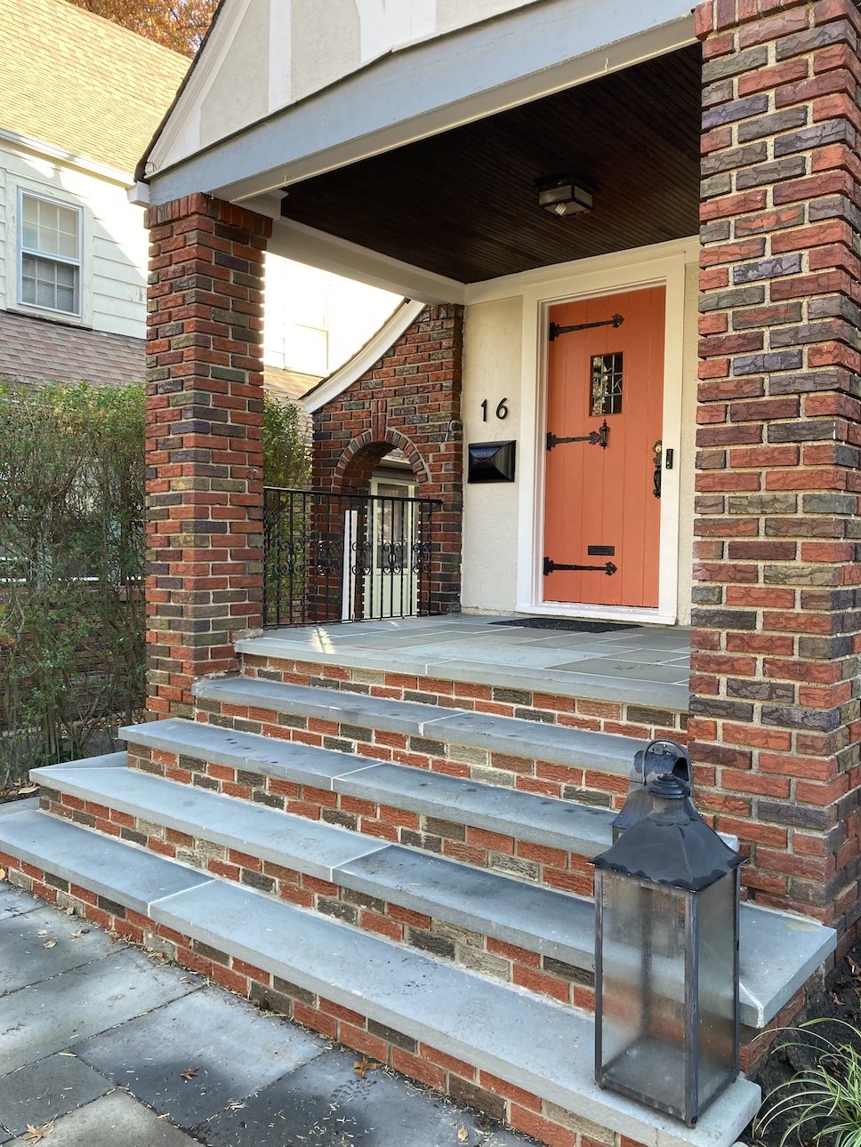Brick step and column entrance to NJ home with red barn door and archways.jpg