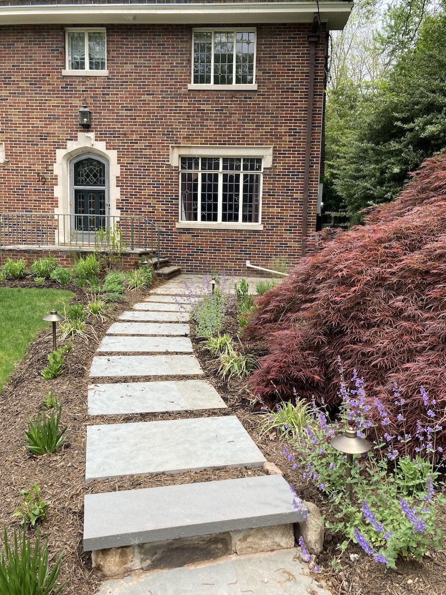 Stone walkway entrance to brick house lined with shrubs and flowers in NJ.jpg