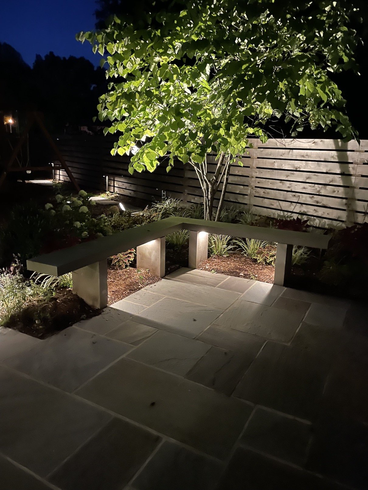 Bench lighting in outdoor patio area with beautiful landscape design, a natural wood fence and stonework in northern nj backyard.jpg