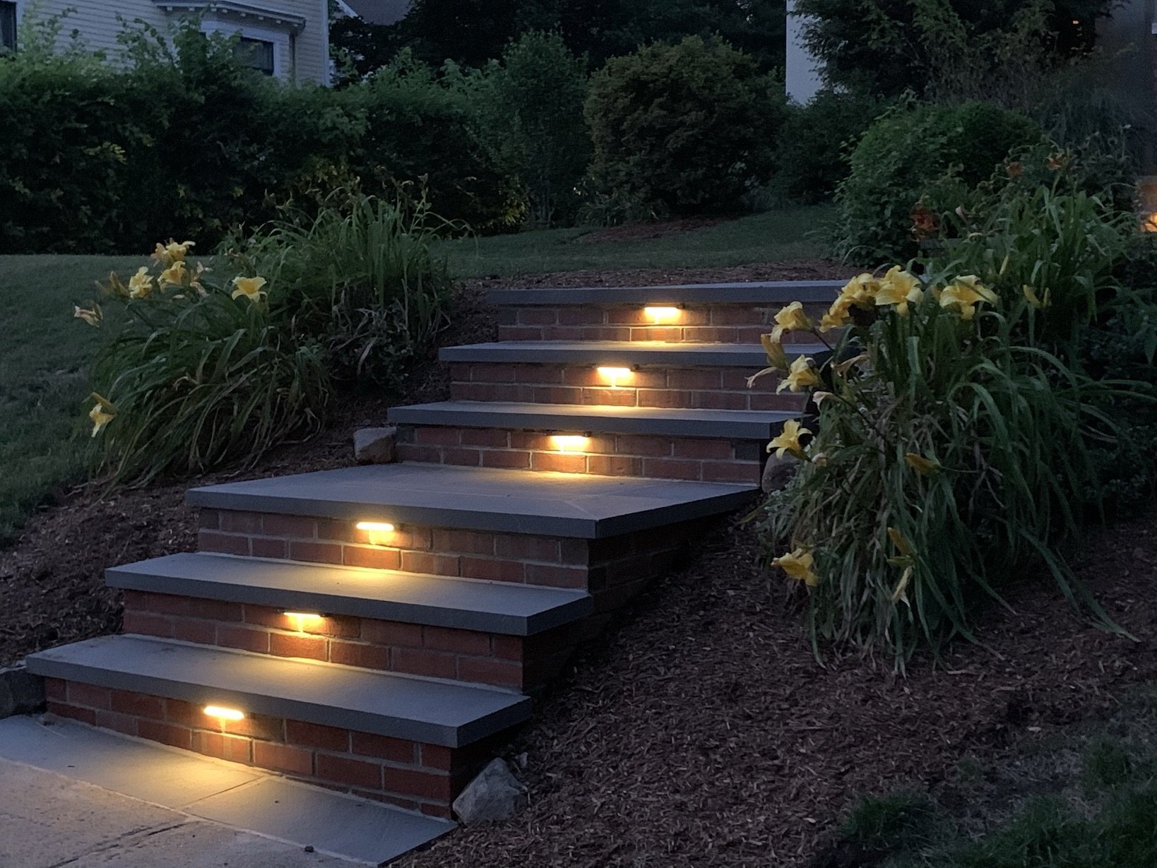 Cap lights on brick steps to highlight front entrance walkway to house at night.JPEG