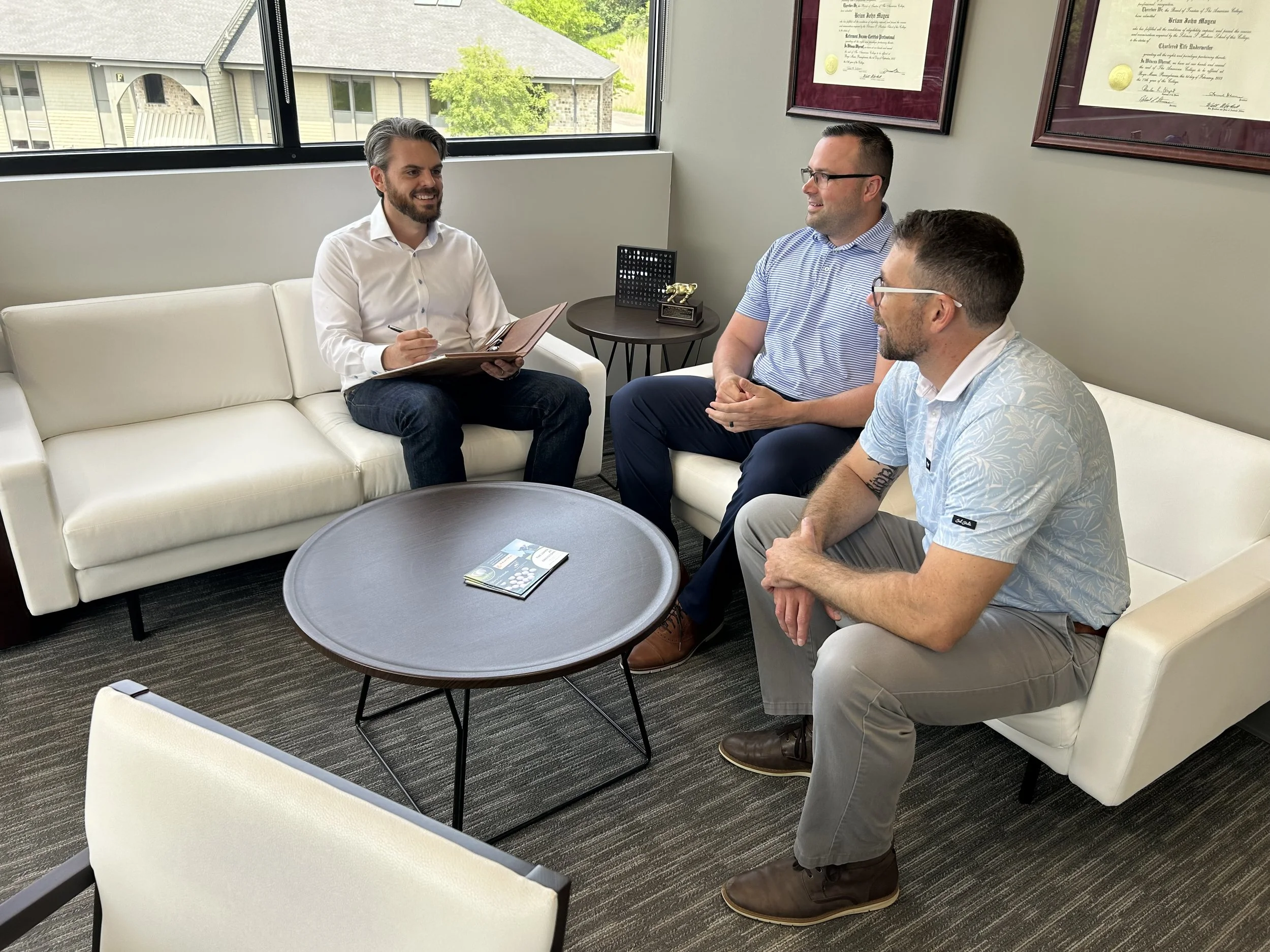 Three men sitting on couches by a coffee table having a discussion.