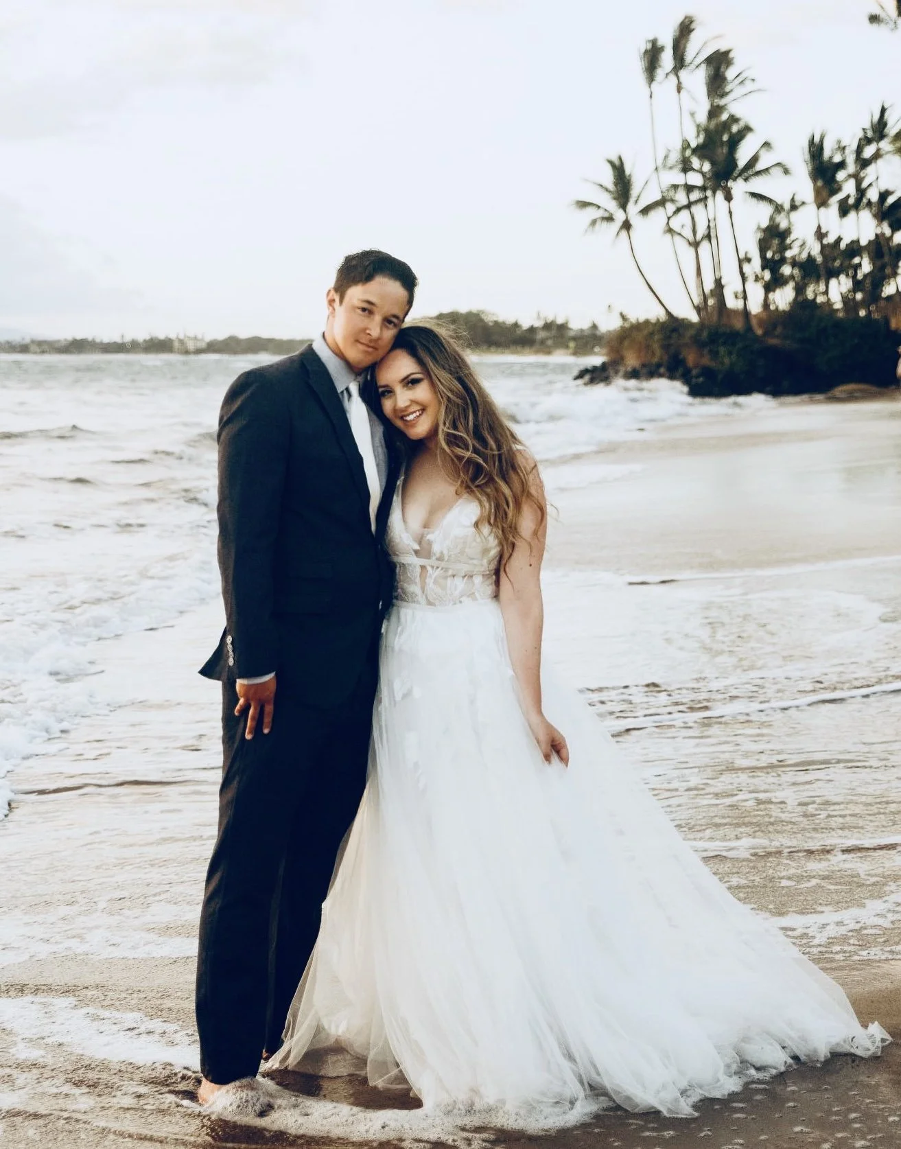 a bride and groom smiling by the ocean