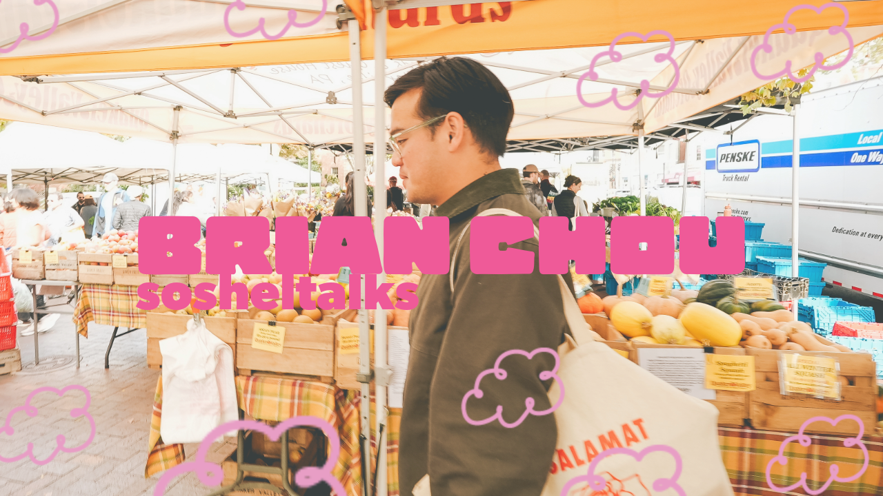 A man shopping at an outdoor farmer's market with fresh vegetables and fruits, under yellow and white tents.