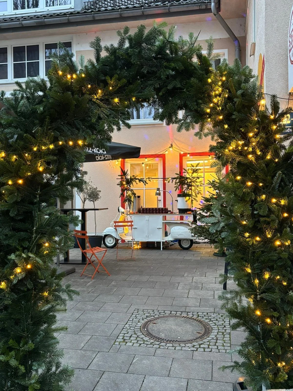 Weihnachtsdeko mit beleuchtetem Tannengbogen als Eingang zu einer Eventlocation. Firmenweihnachtsfeier-Ausstattung mieten mit stimmungsvoller Outdoor- und Eingangsdekoration.