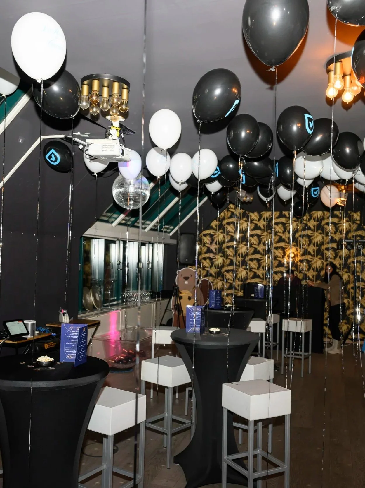 Moderne Partyfläche mit Ballondekoration, Stehtischen und Barhockern in einer Eventlocation. Firmenfeier-Ausstattung mieten mit Stehtischen, Hockern und Deko für After-Work und Jubiläen.