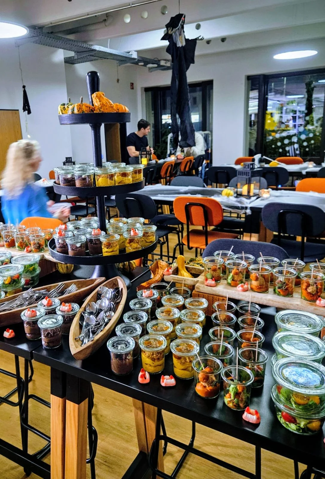 Büfett mit verschiedenen kleinen Gläsern und Tellern mit Speisen, auf einem Tisch in einem festlich dekorierten Raum.